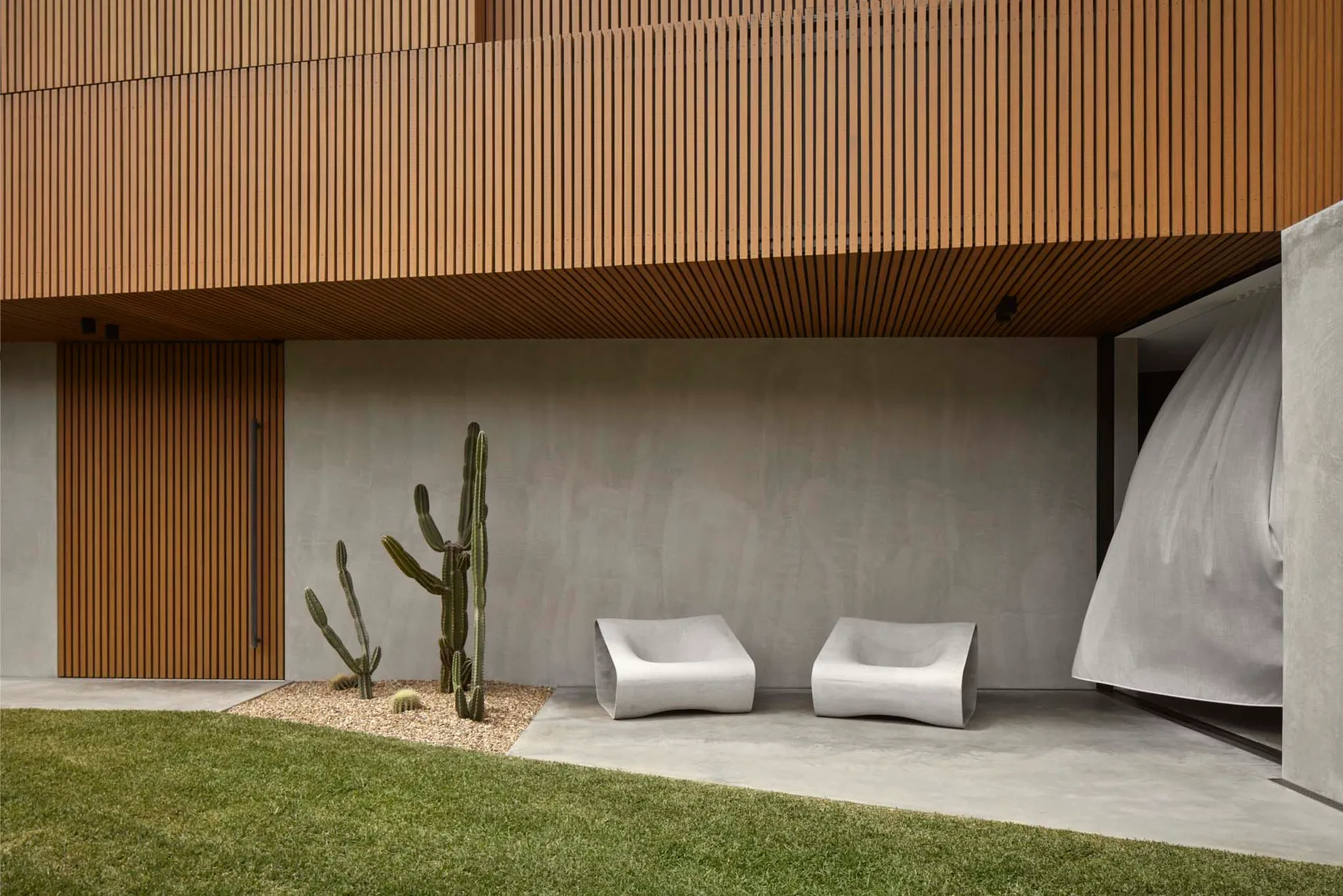 Modern, minimalist residential outdoor space featuring concrete elements and cacti plants.