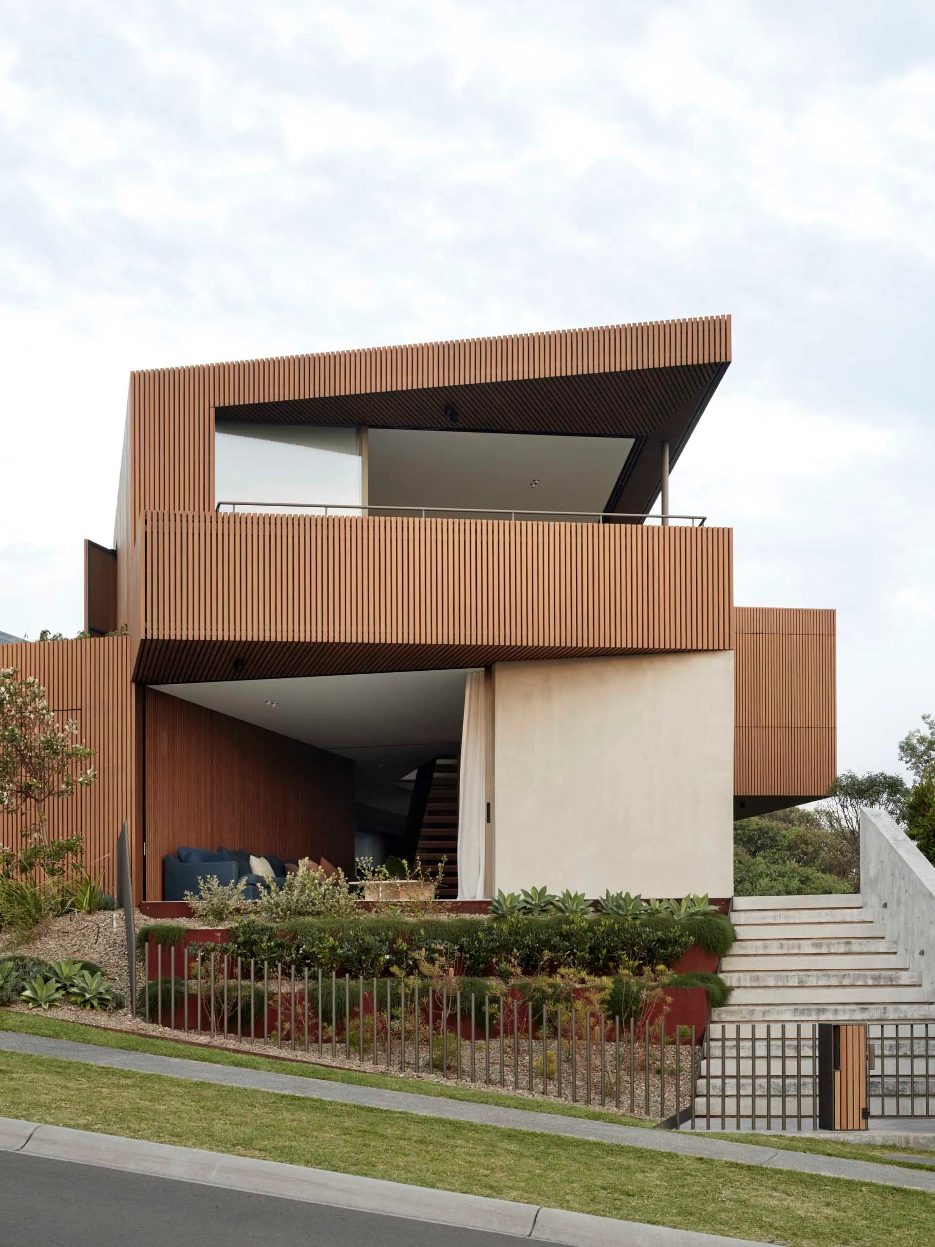 Modern residential house with wood siding, concrete steps, and minimalist architectural design.
