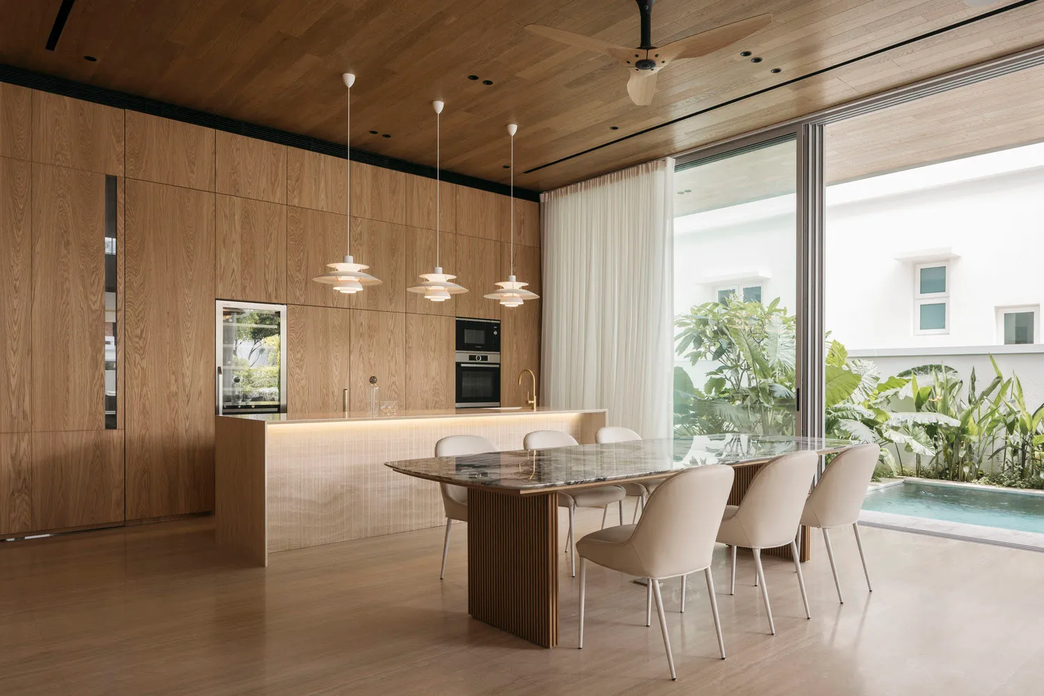 Modern dining room with wooden walls, marble dining table, and white chairs.