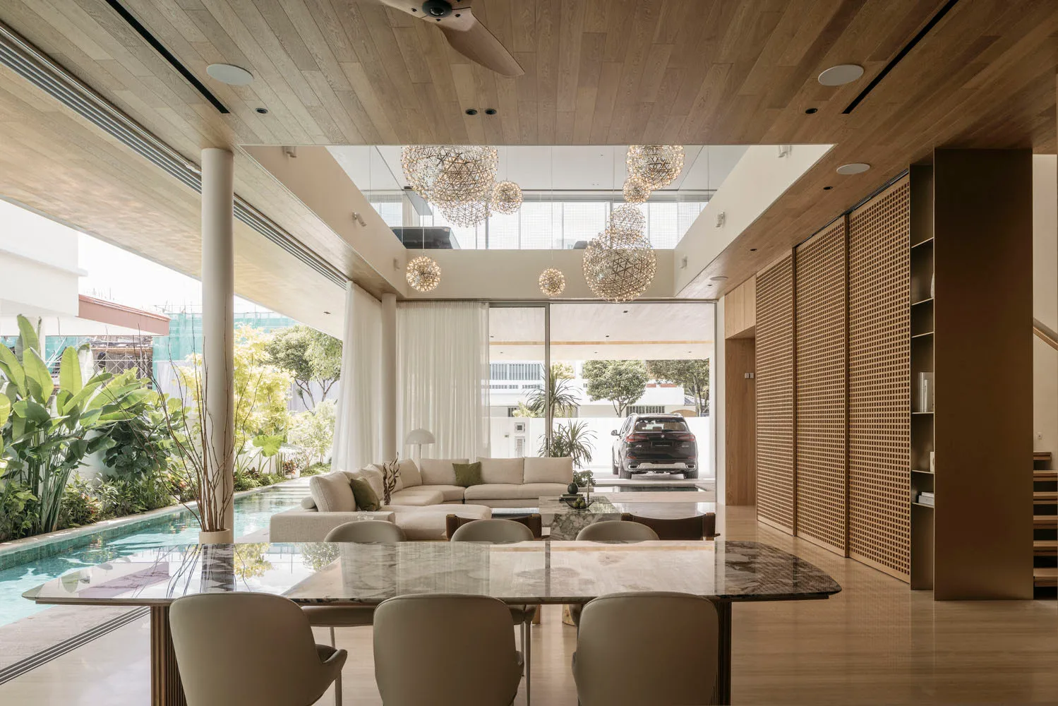 A modern living room featuring wooden furniture, glass walls, and a large sofa.