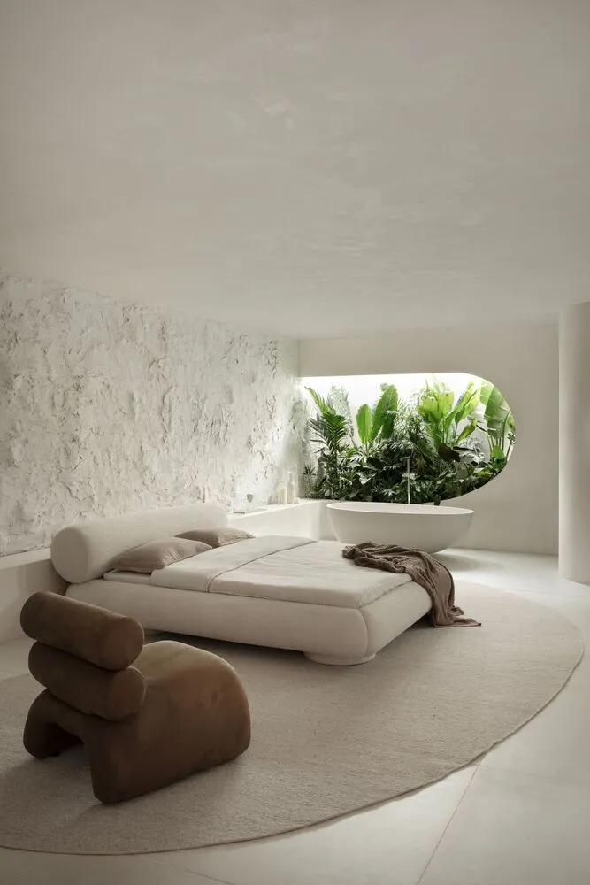 A modern minimalist bedroom with a concrete bed frame and plant-filled bathtub
