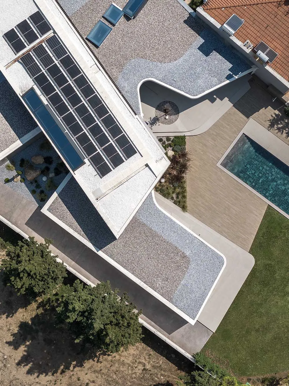Modern private residence with concrete rooftop featuring solar panels and a geometric outdoor space.