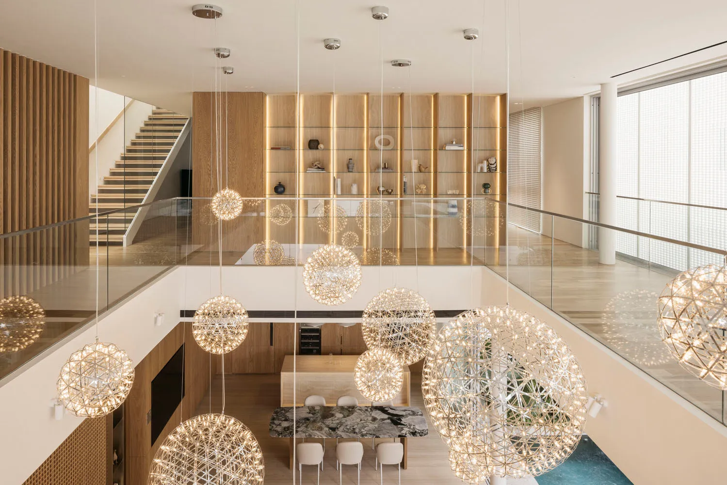 Modern residential interior featuring metallic light fixtures, wooden furniture, and a glass canopy.