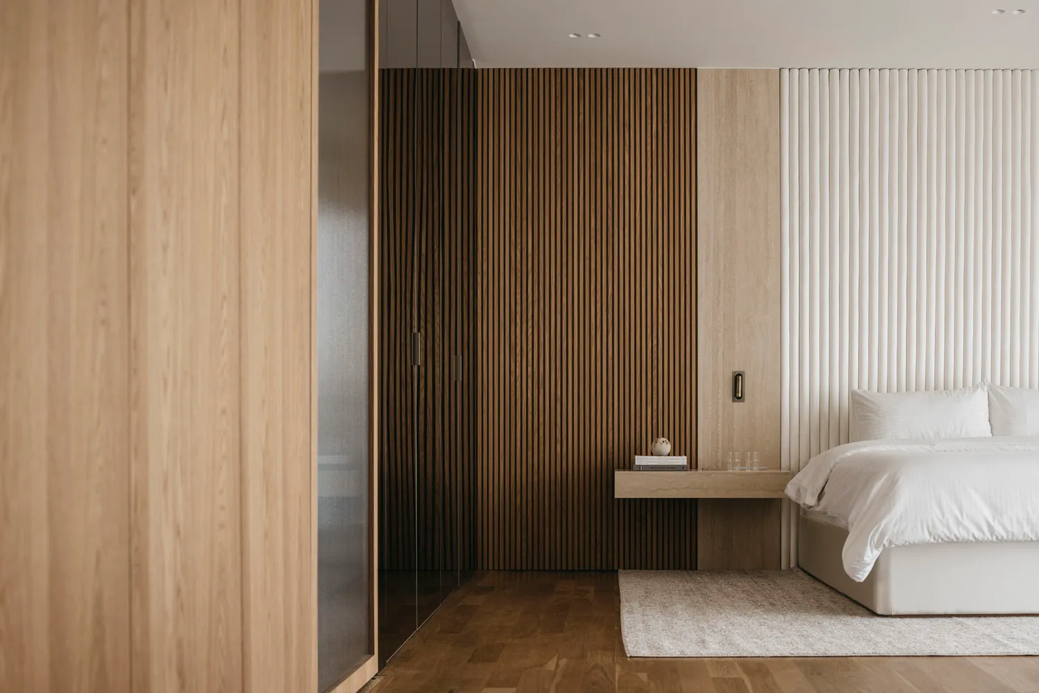 A modern bedroom featuring wooden panels and a minimalist design.