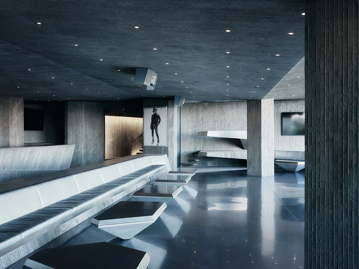 Modern, industrial-style interior with concrete walls and floors, featuring sleek, minimalist furniture and a dramatic, monoc