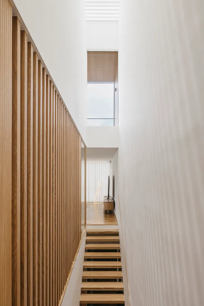 Modern interior design with minimalist white space featuring wood elements and a high window.