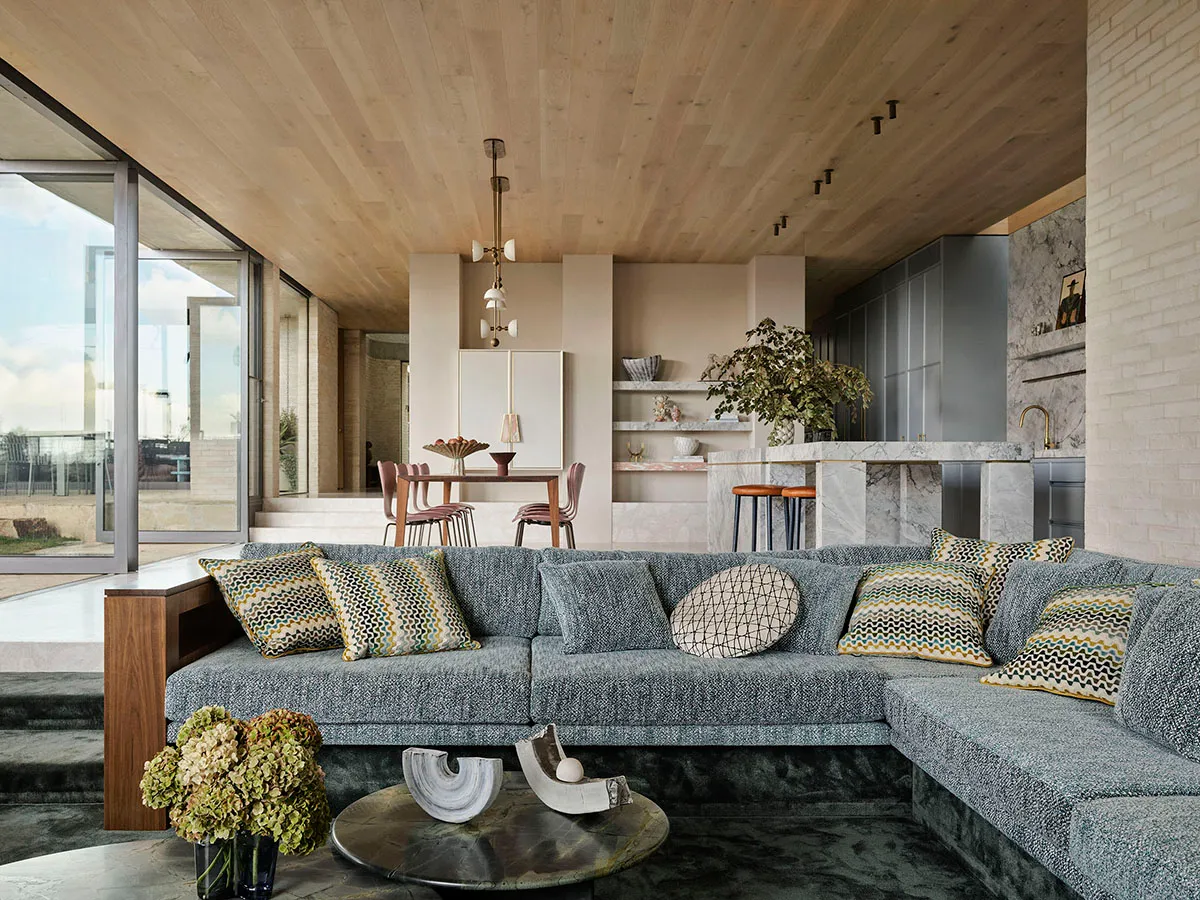A modern living room with a large sectional sofa, patterned cushions, and a round coffee table.