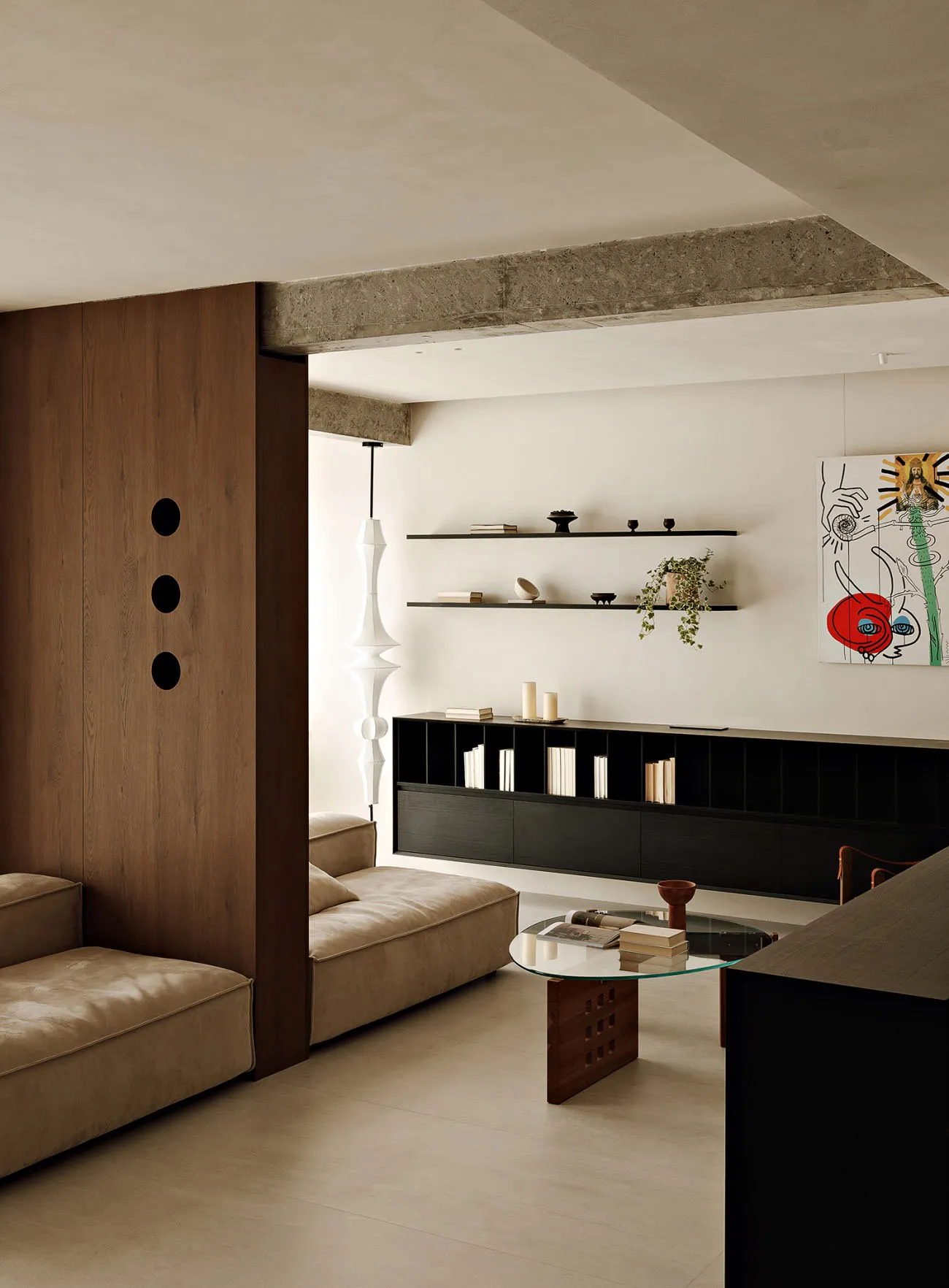 Modern living room featuring dark wood joinery, concrete ceiling beams, minimalist furniture, and a glass coffee table.