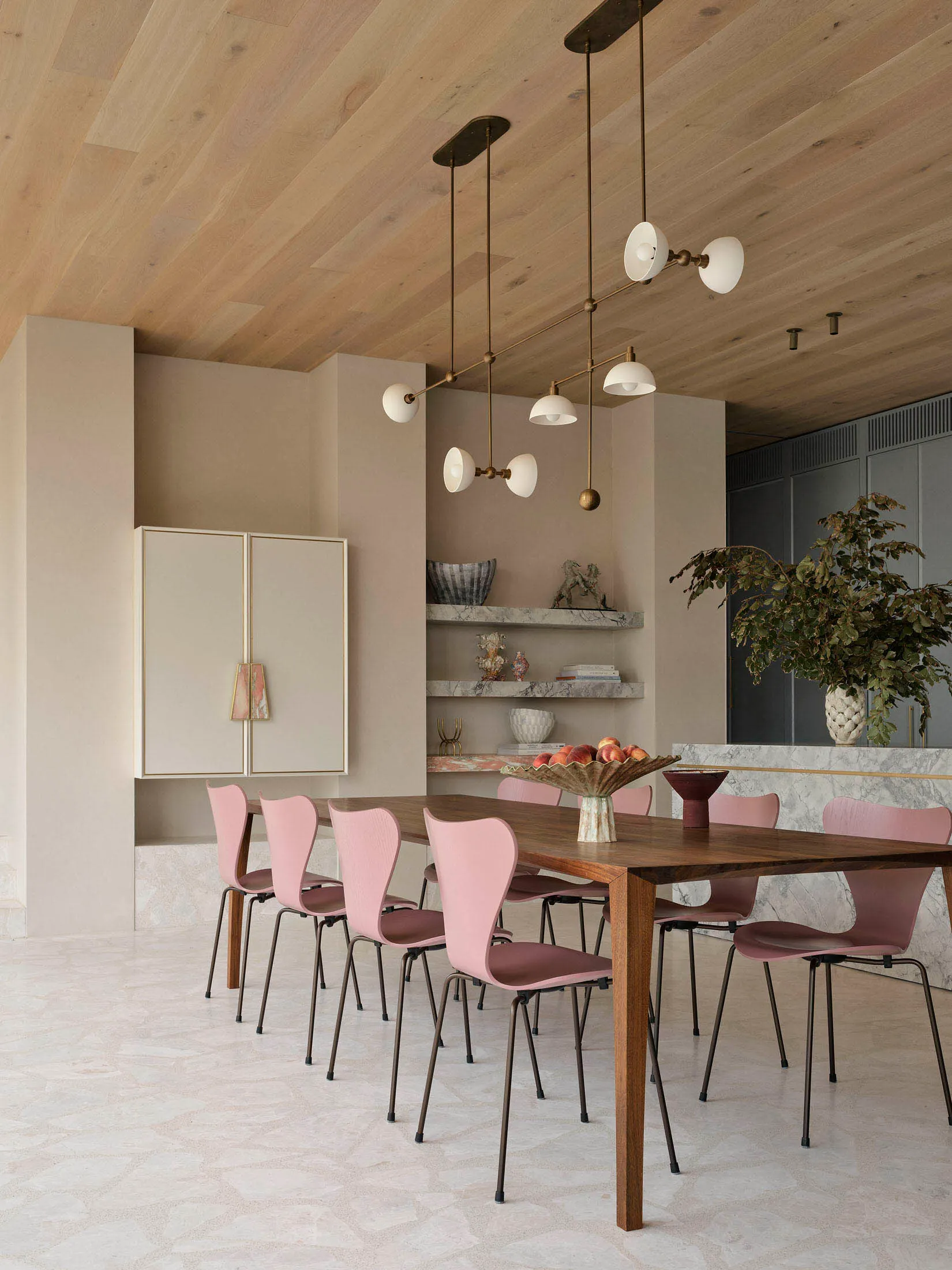 A modern minimalist dining room with wooden table, marble accents, and metal pendant lights.