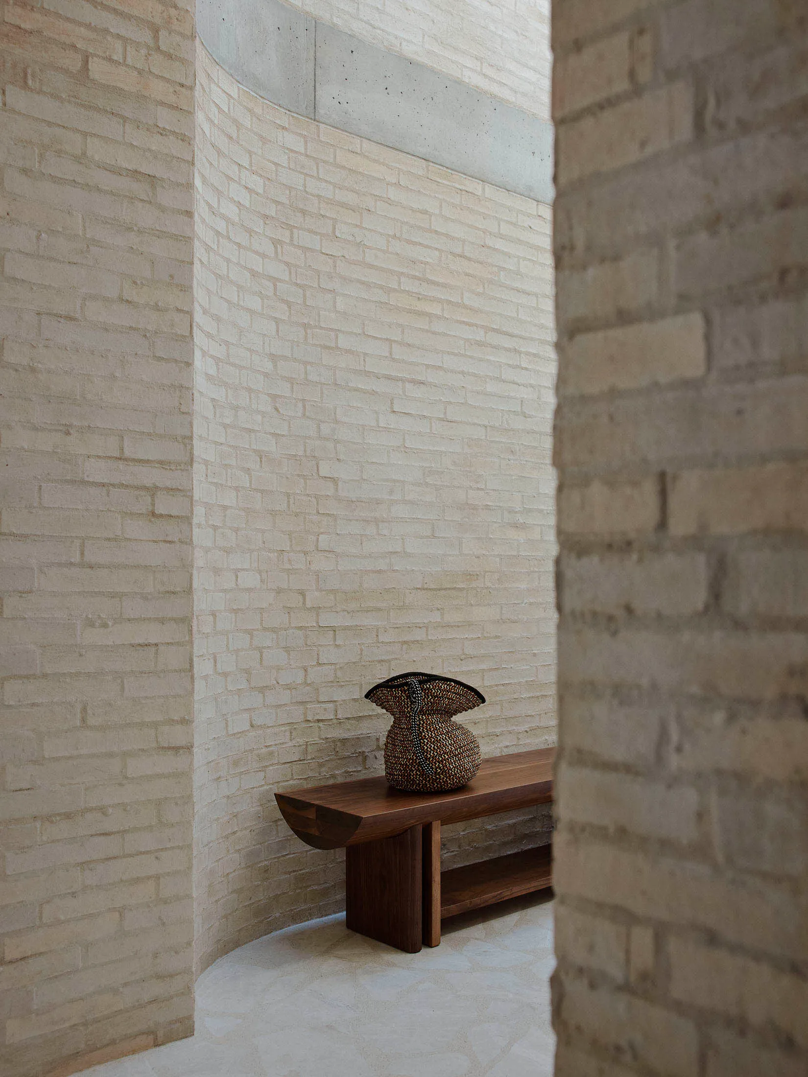 簡約室內空間,擺放木質長椅,椅上置有編織籃。