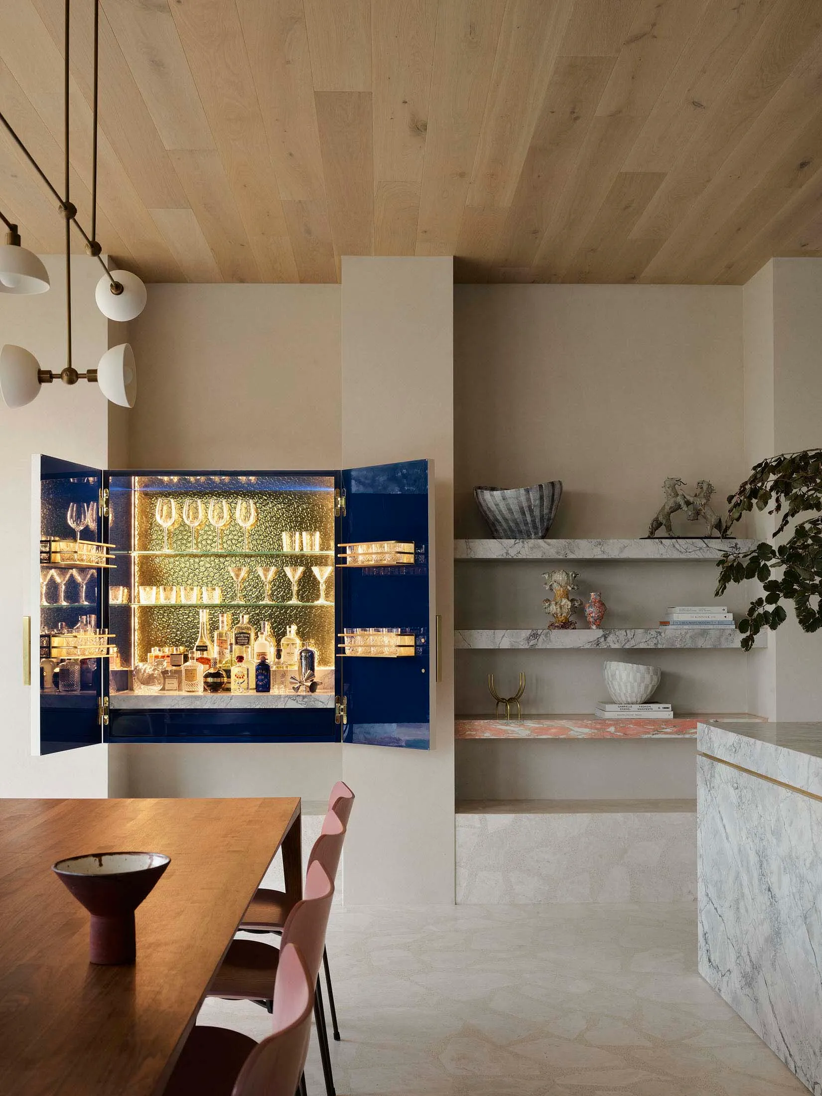 A modern interior design featuring a living room with a bar area equipped with marble, concrete, and wooden elements.