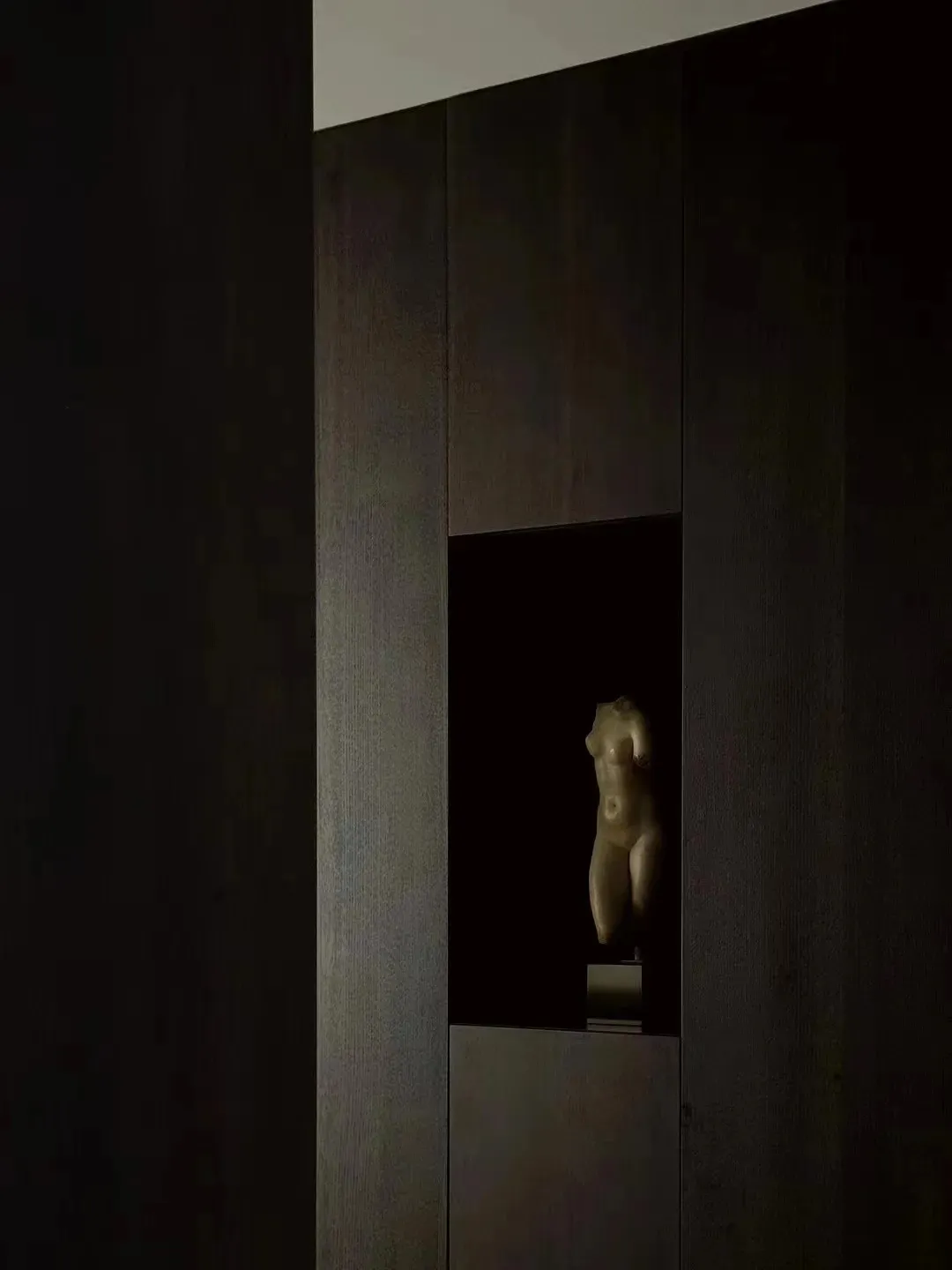 A carved wooden sculpture embedded in a dark wooden wall