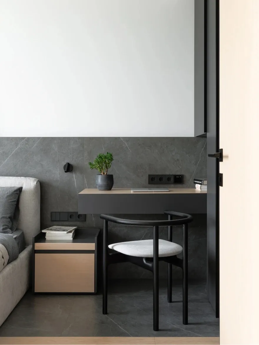 A minimalist workspace with a marble desk, wooden chair, and metal accents