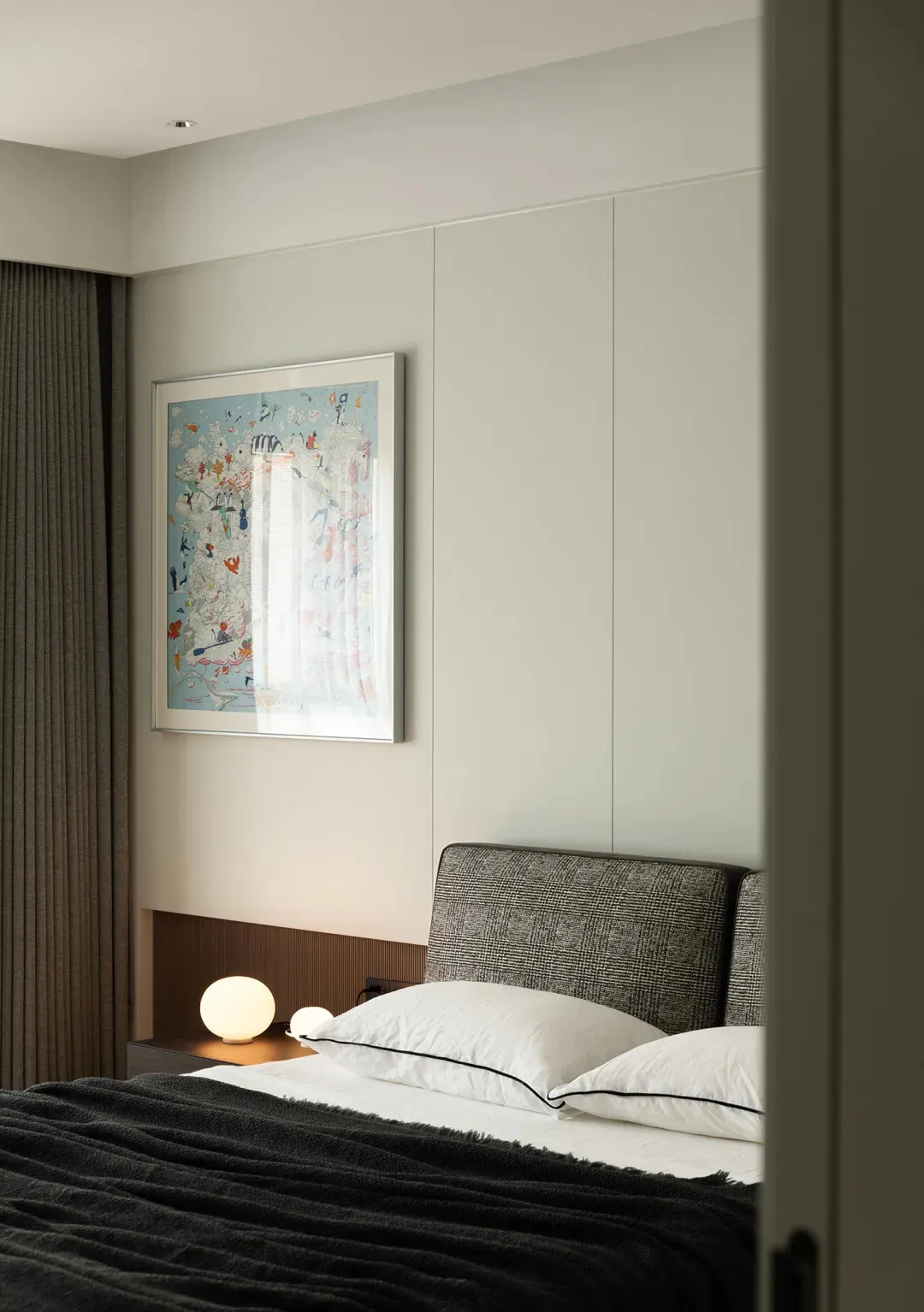 Minimalist bedroom with a textured grey bedspread, white pillows, and a contemporary artwork.