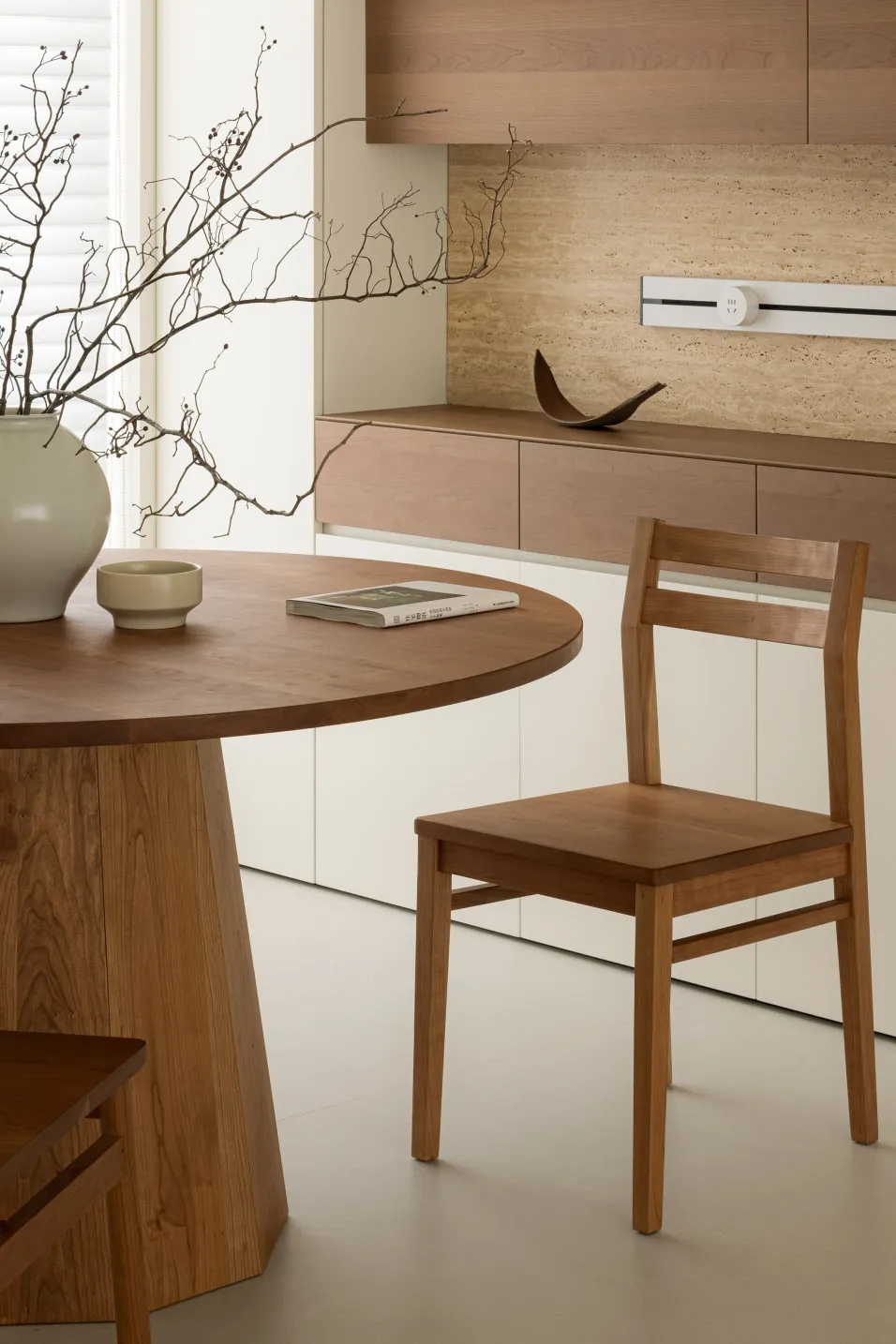 Modern minimalist dining room featuring a round wooden table, wooden chairs, and minimalist decorations.