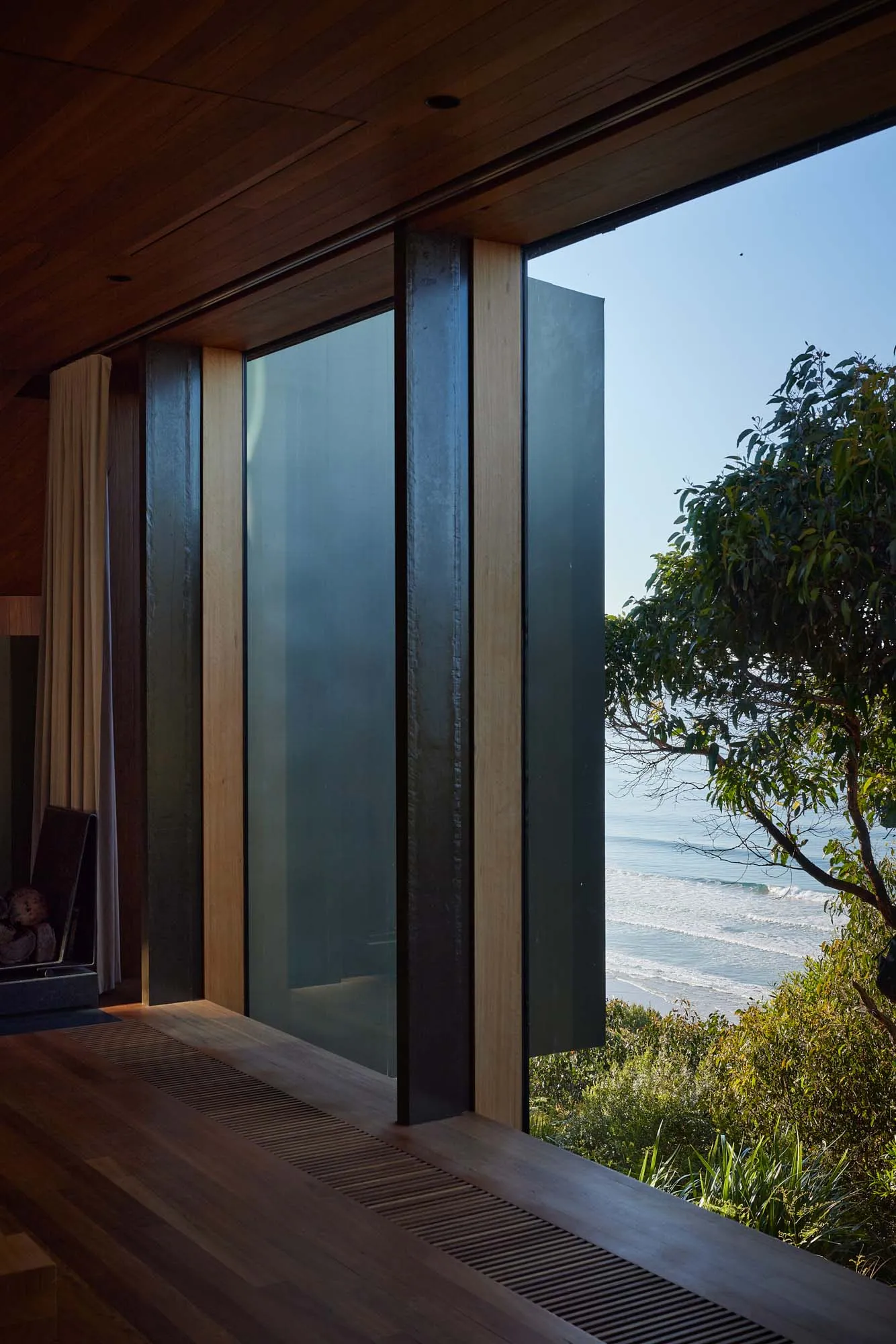 A modern window design with a glass view of the ocean and lush greenery.
