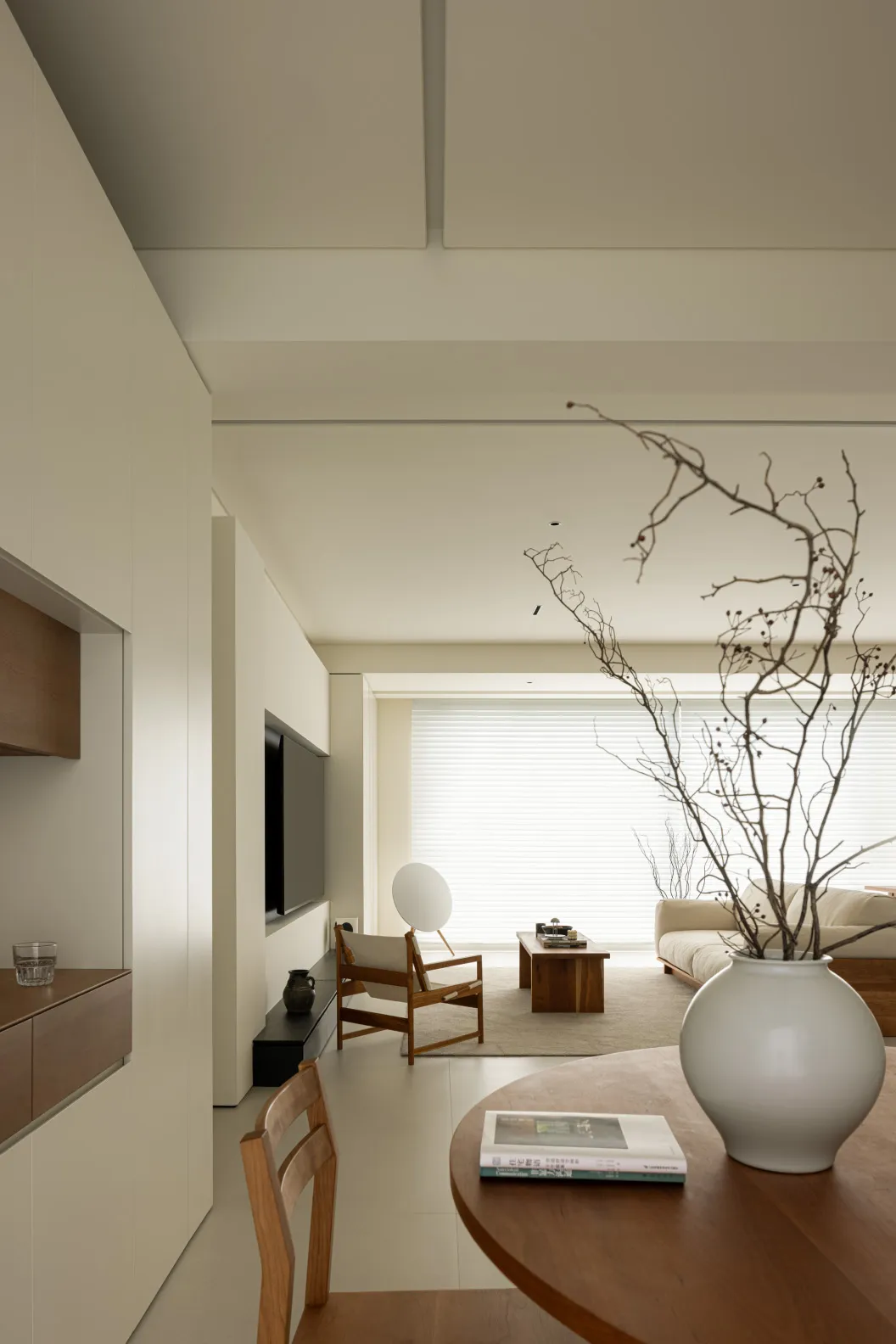 A minimalist living room featuring wood furniture and glass elements.