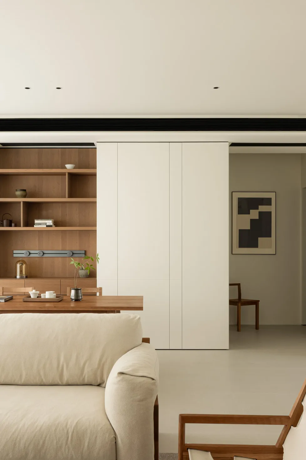 A modern minimalist living room with wooden furniture, a white sofa, and a wooden coffee table featuring a small plant.