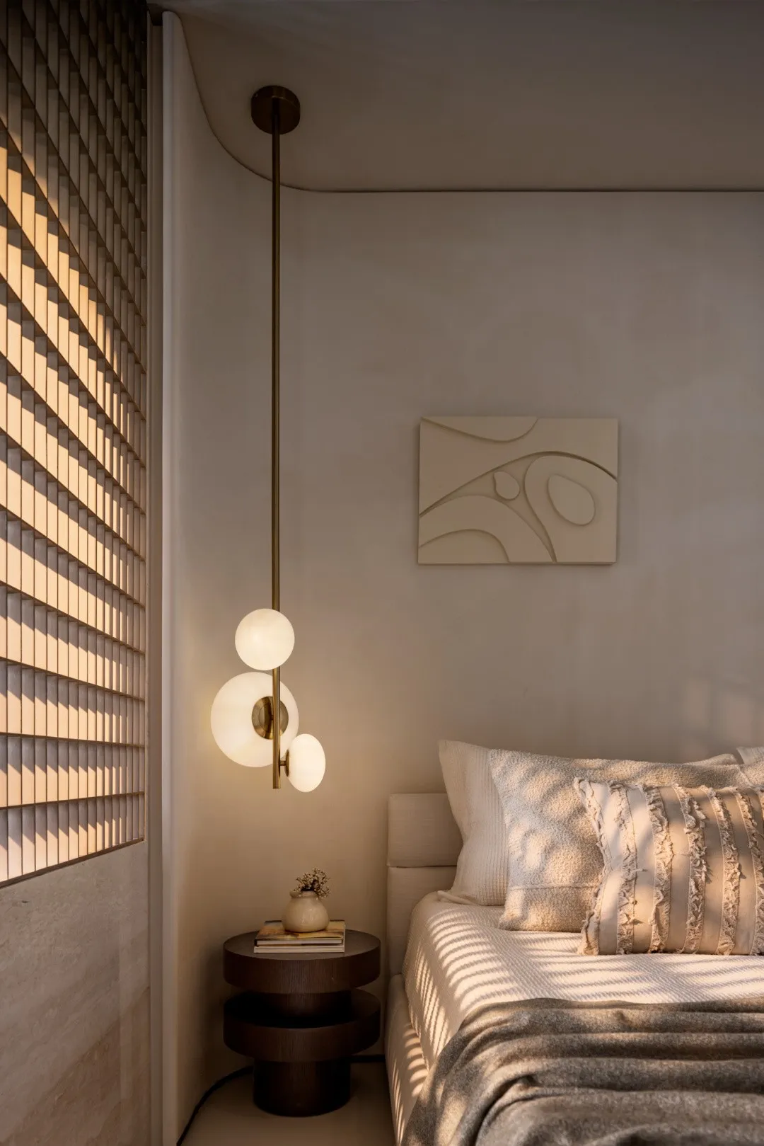 A minimalist bedroom featuring a bed with textured fabric cover and a hanging light fixture.