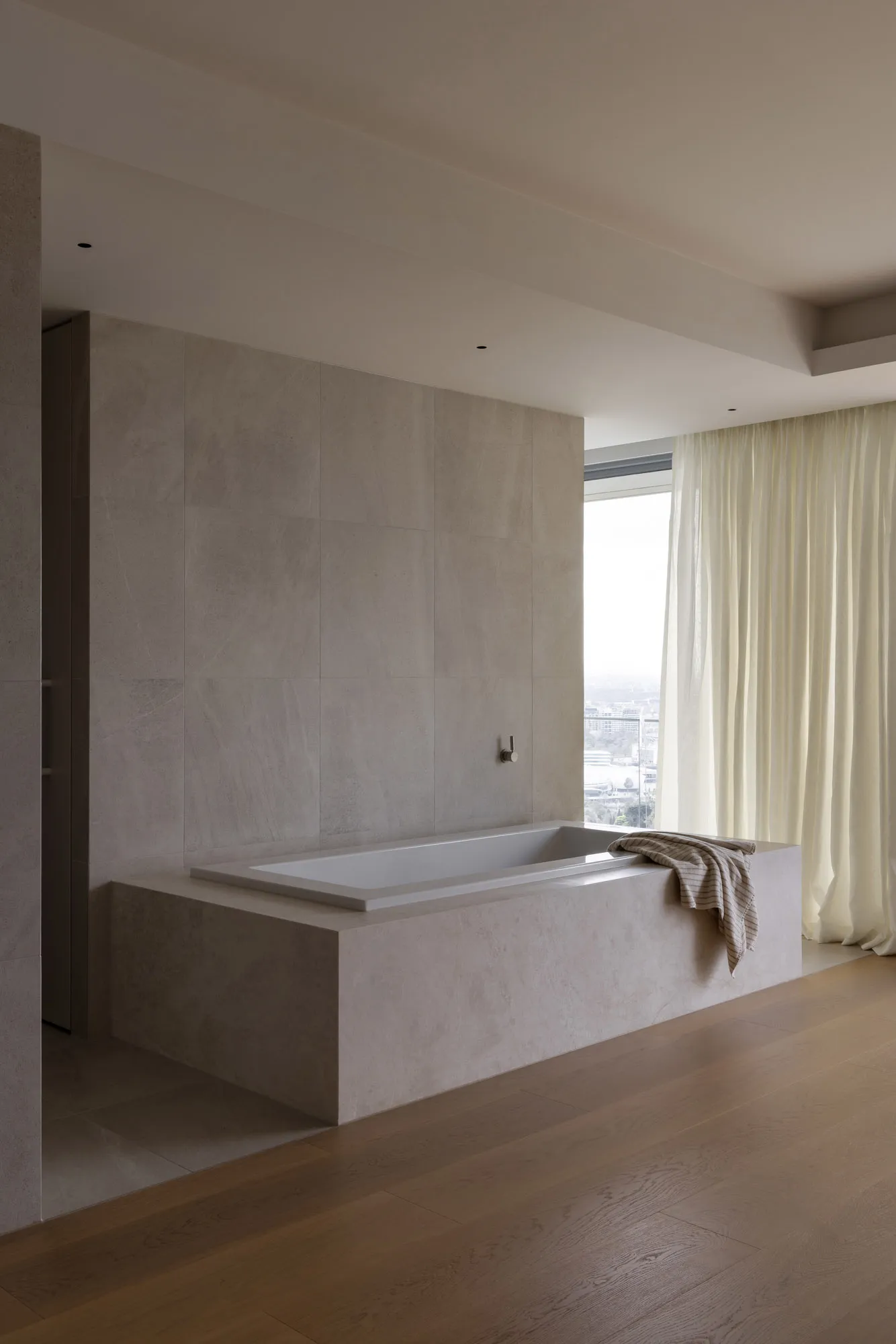 A modern bathroom with a concrete wall and built-in tub, featuring minimalistic design with natural light.