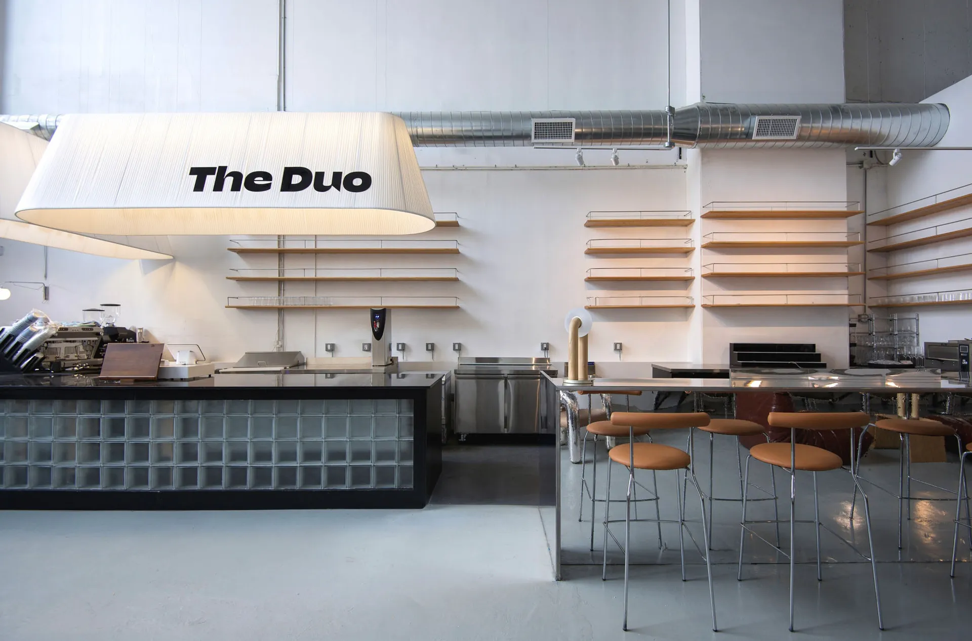An interior of a modern coffee shop with a glass counter and wooden shelves.