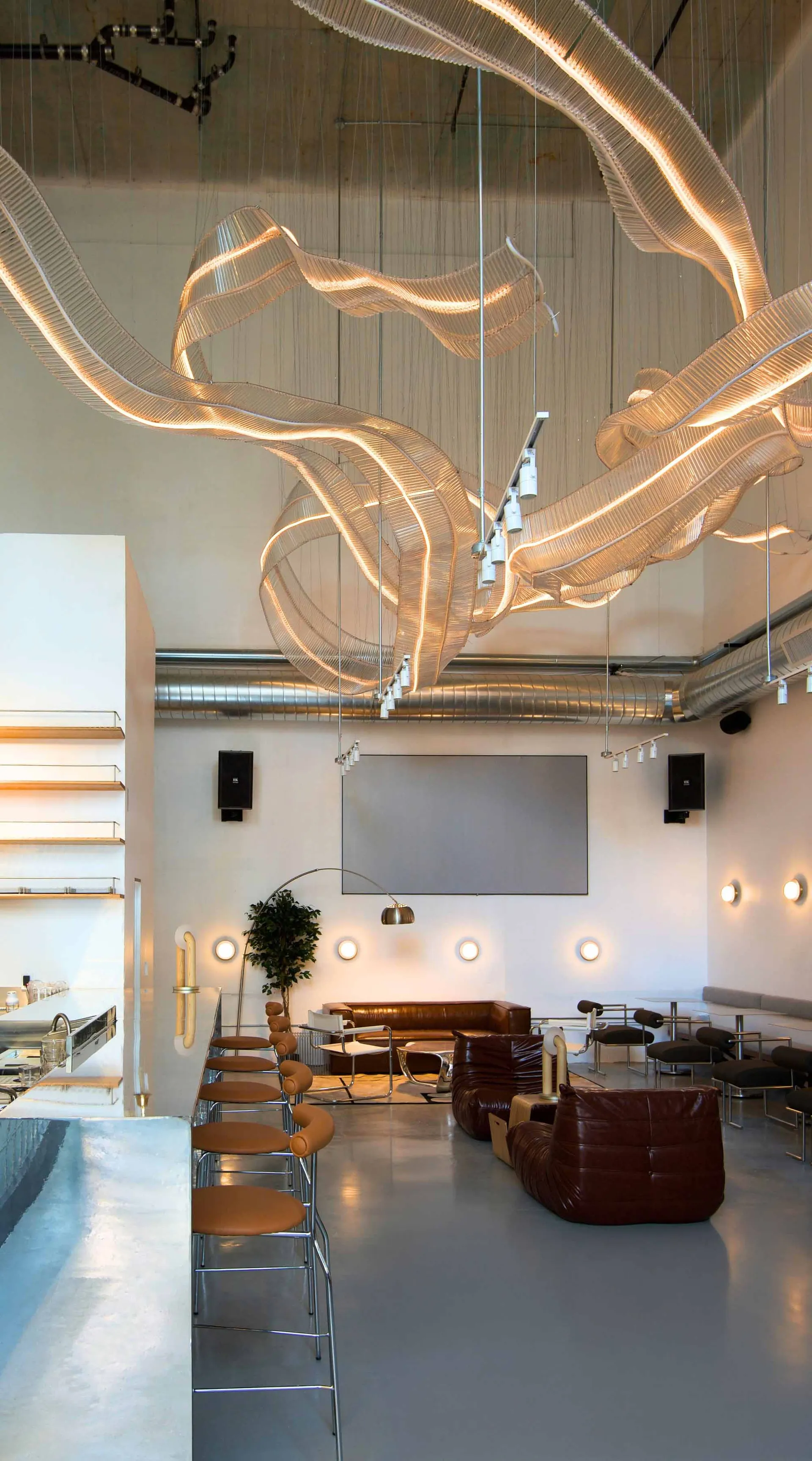 A modern industrial coffee shop with a large glass ceiling and contemporary seating arrangements.