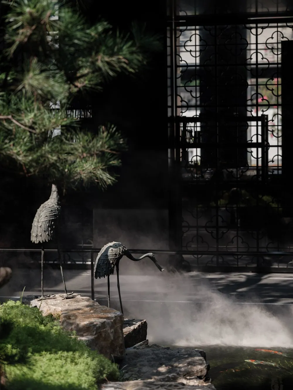 A peaceful modern landscape featuring stone birds and water features.