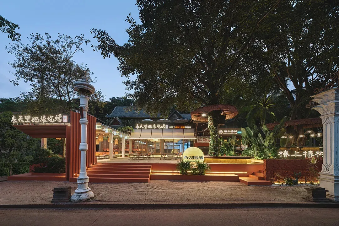 Industrial-style restaurant exterior made of concrete, featuring modern design elements and a large tree for shade.