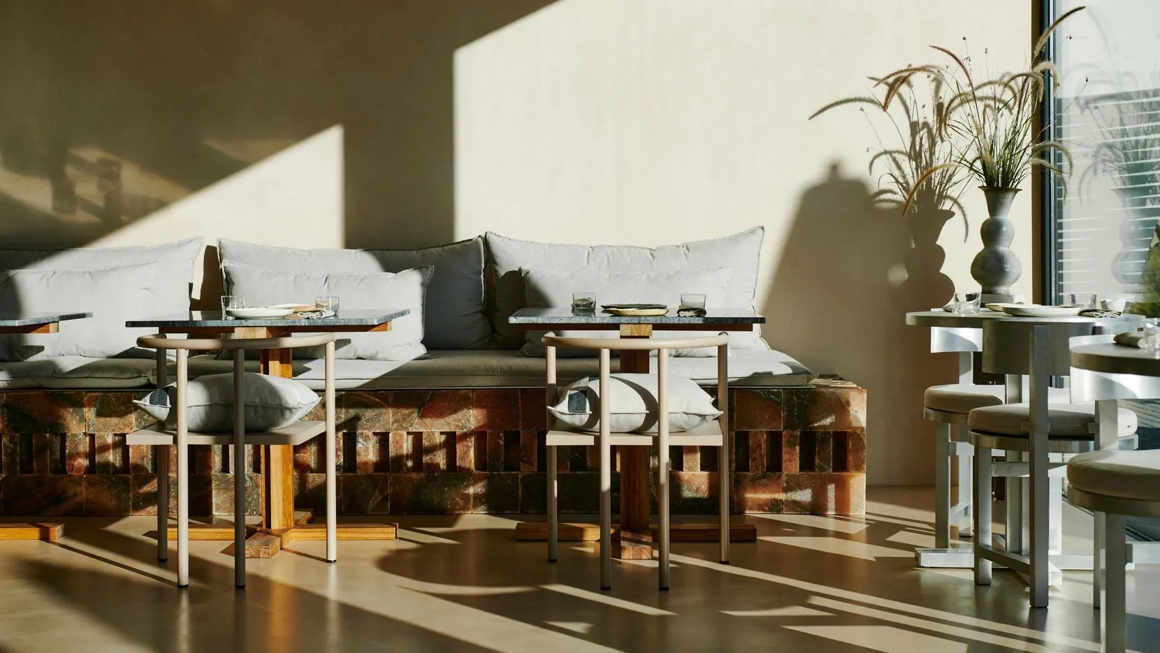 A modern cafe interior with wooden seating and marble tables and countertops.