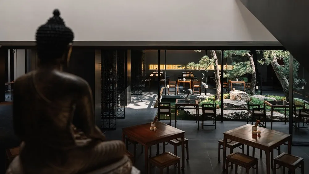 現代簡約餐廳室內,搭配木質家具與寧靜的戶外中庭。
