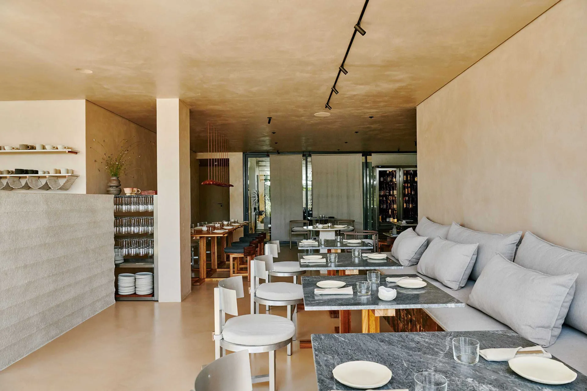 A modern restaurant interior featuring concrete walls and floors with tables set for dining.