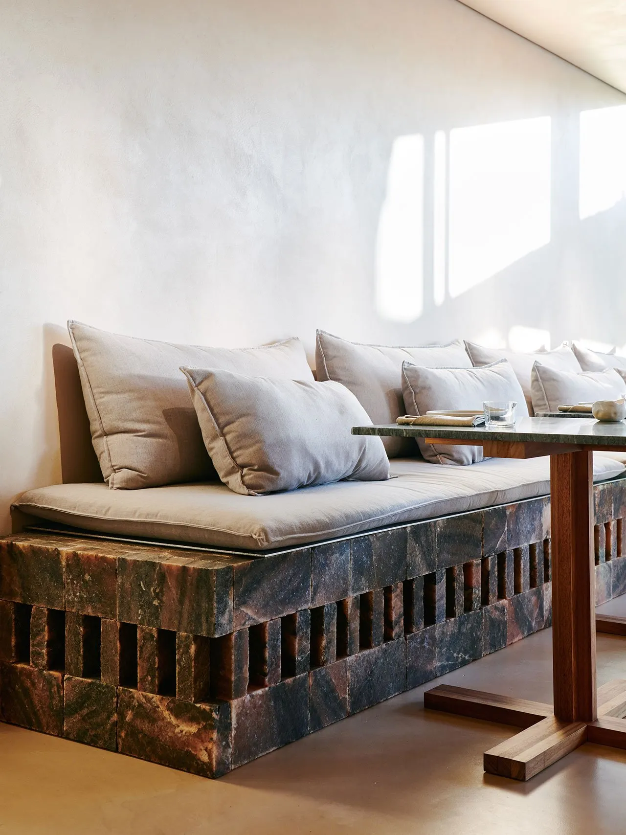 A modern living room with concrete seating area and light-colored cushions.