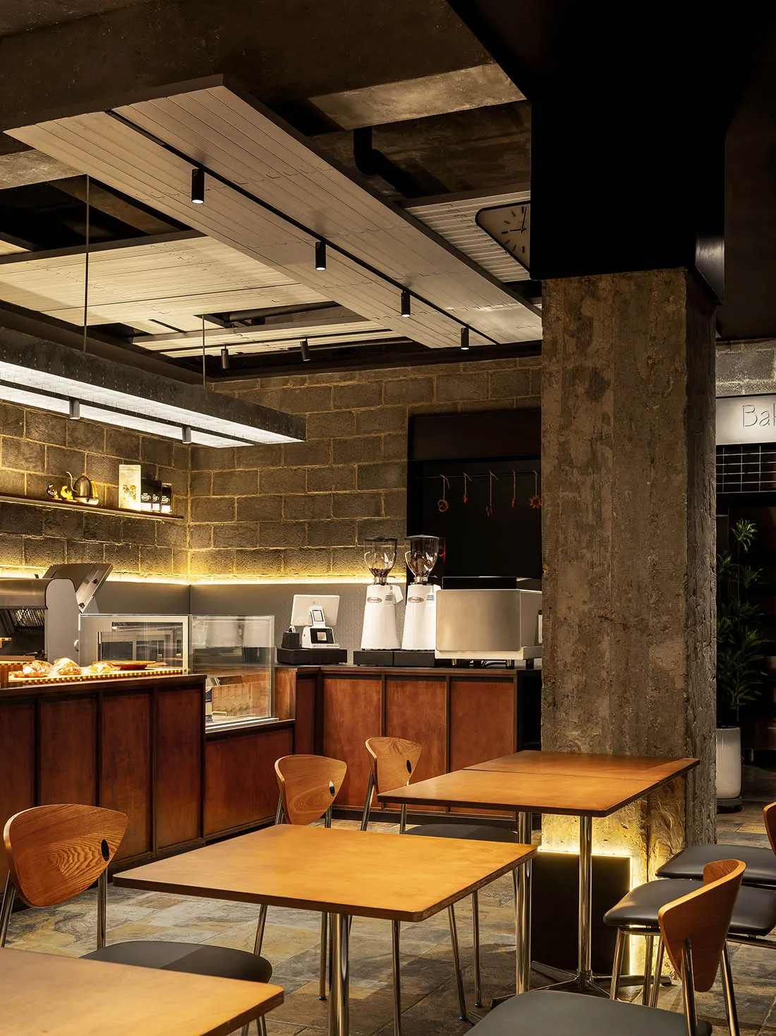 Industrial-style coffee shop with concrete walls, wooden tables, and metal stools.