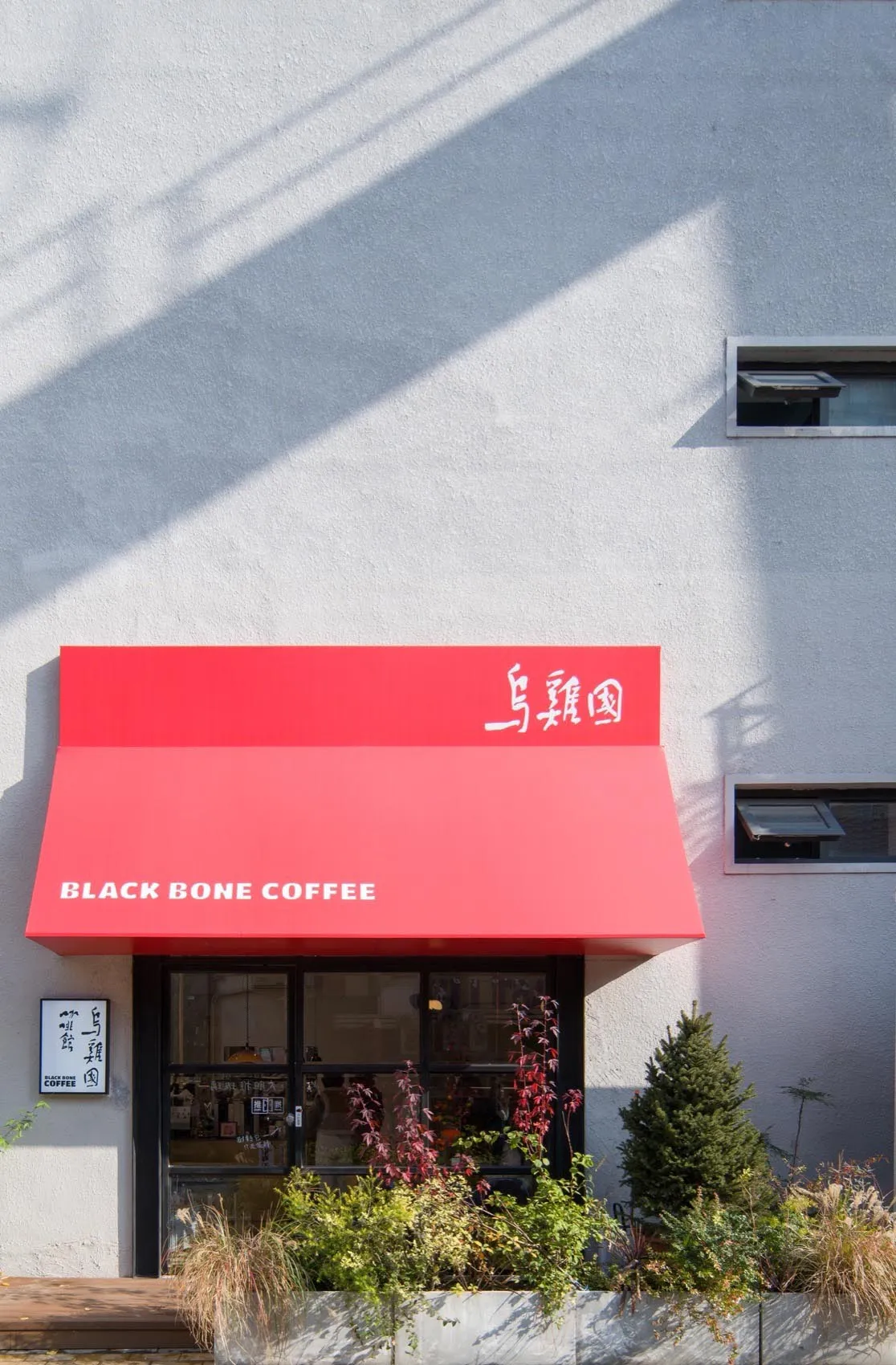 現代咖啡店門面，配有紅色遮陽篷與玻璃前門。