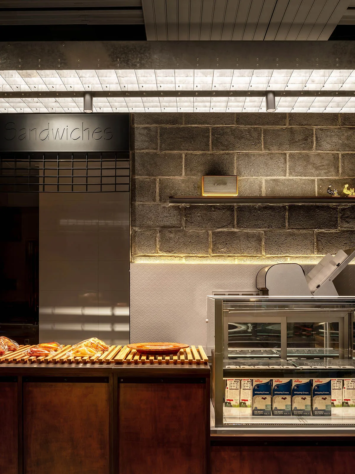 Sandwich shop with a concrete and steel interior design, featuring exposed brick walls and bright lighting.