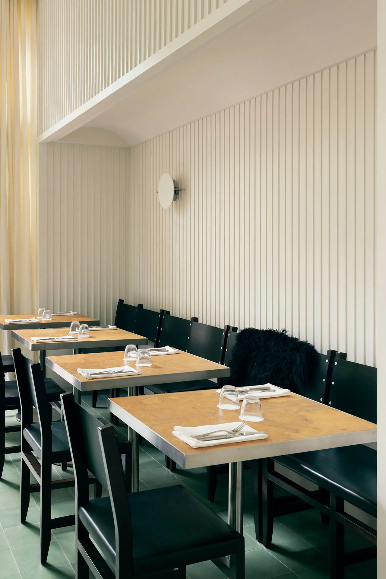 A modern restaurant interior with wooden tables and chairs.