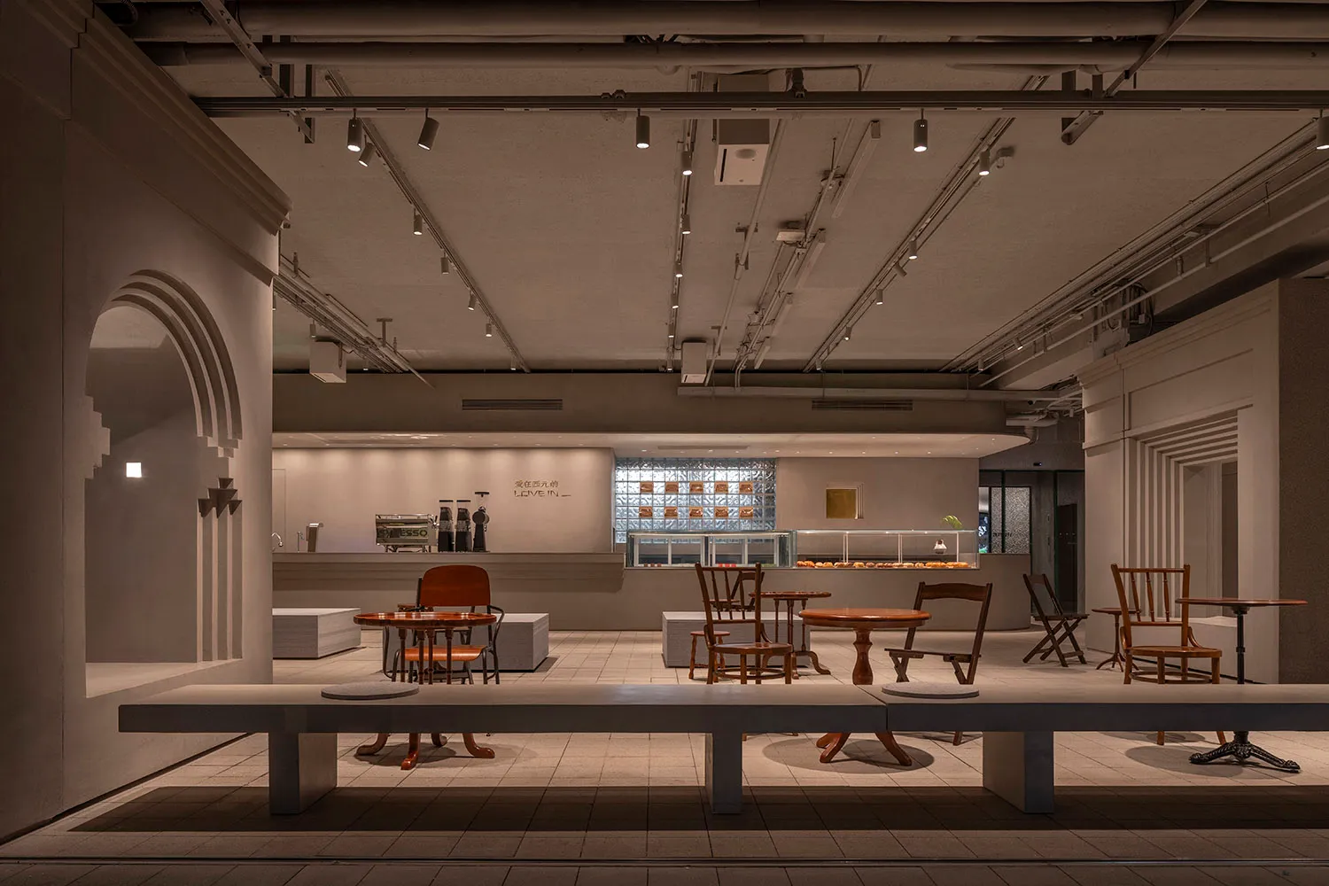 Minimalist coffee shop interior with concrete materials and industrial lighting.