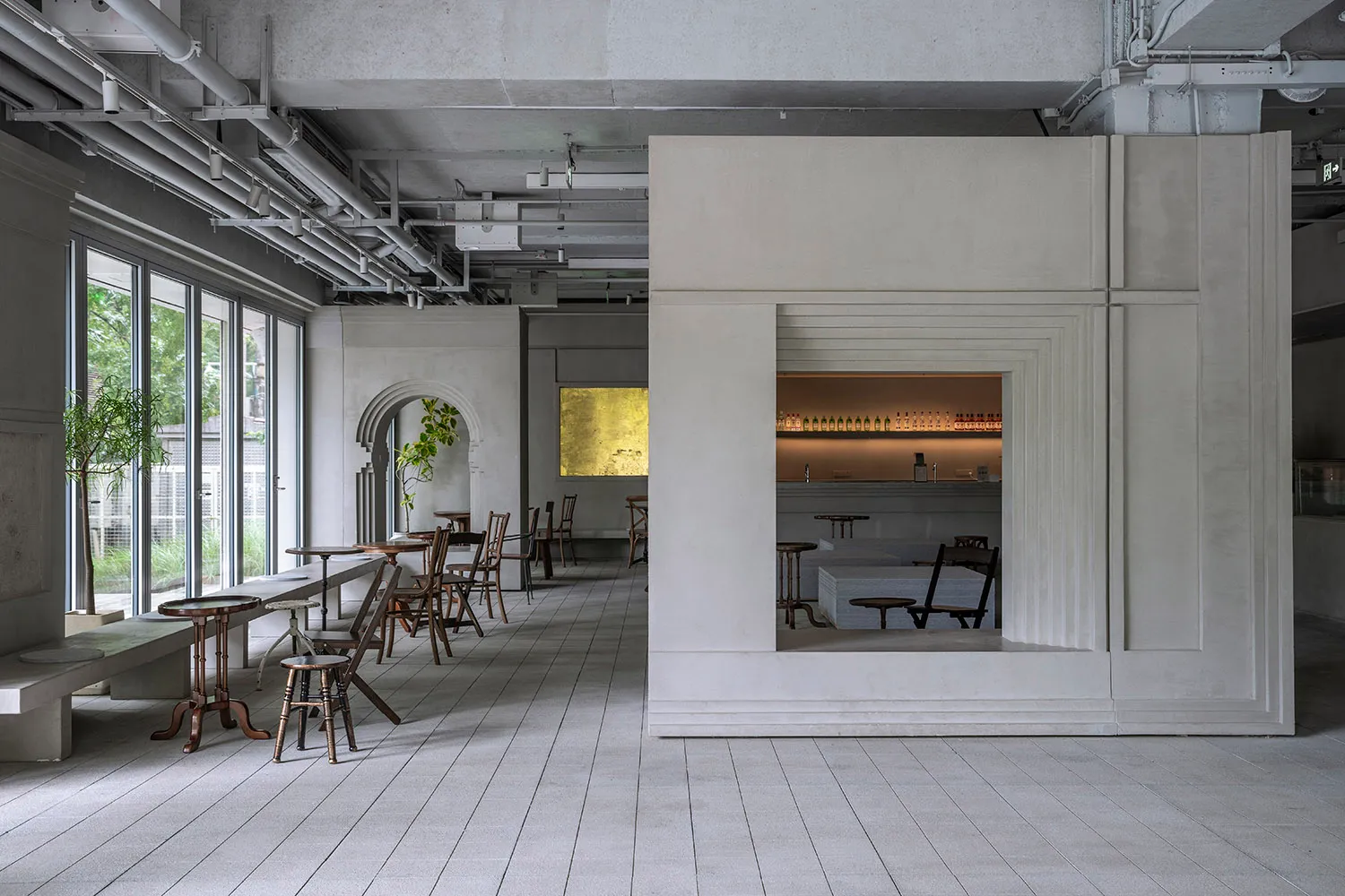 A modern restaurant bar interior with concrete walls and seating areas.