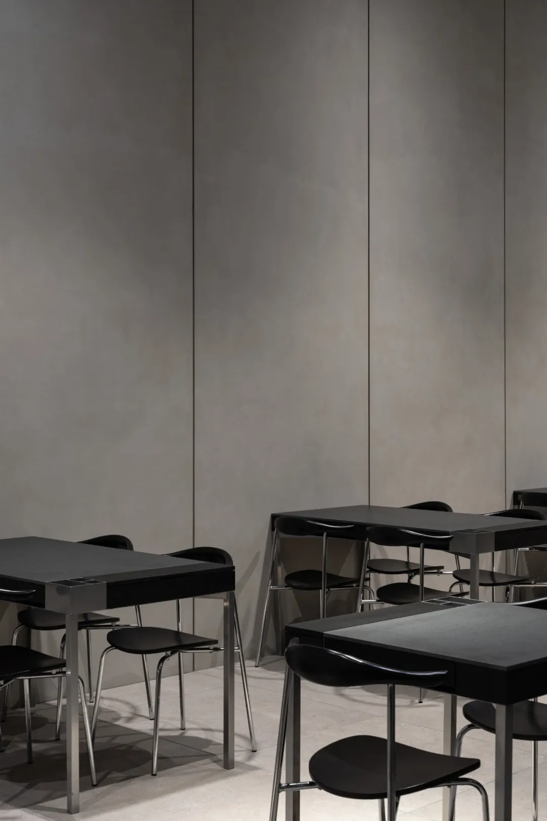 Modern, minimalist industrial restaurant interior with metal tables and chairs.
