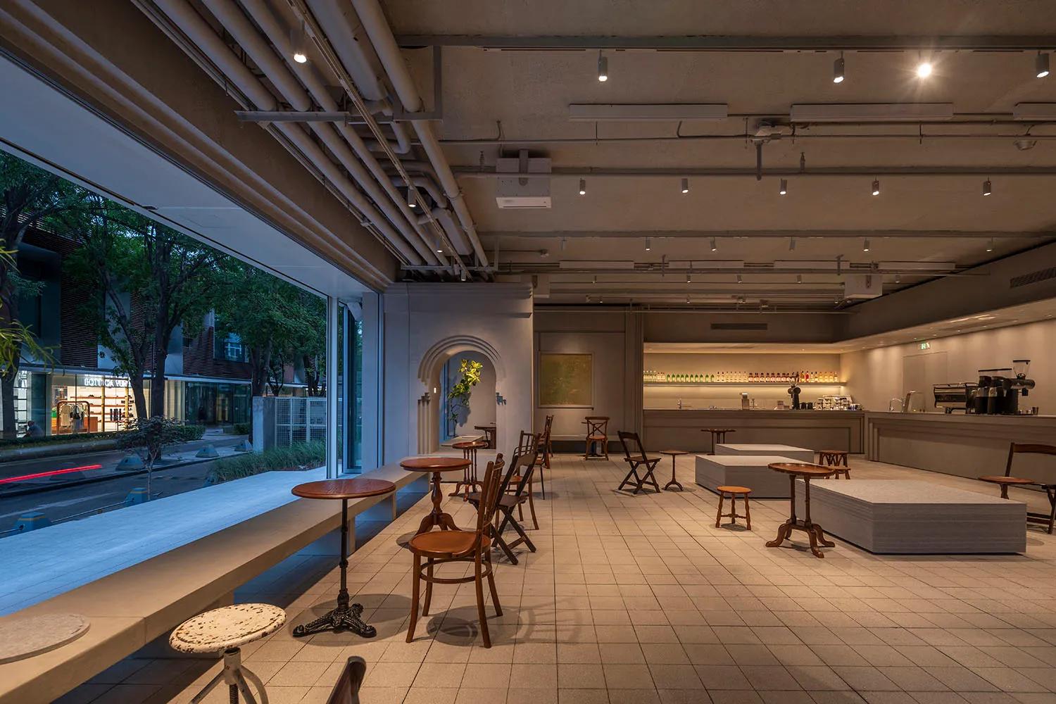 Modern minimalist restaurant interior with concrete walls, wooden tables, and industrial lighting.