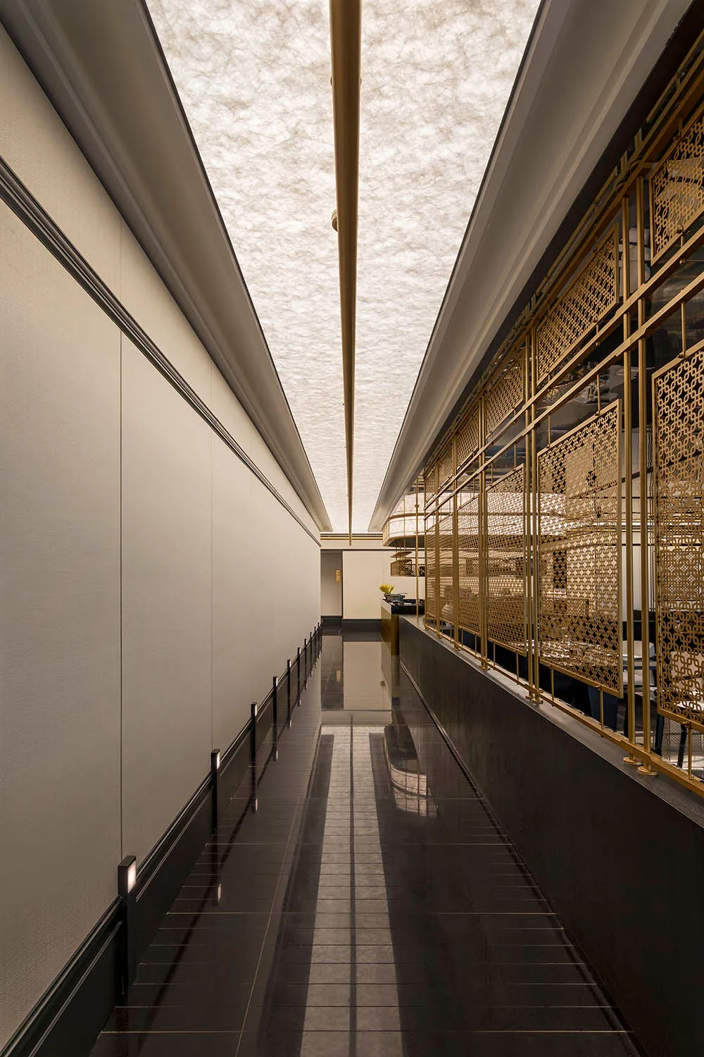 A modern interior design of a corridor featuring ceramic tiles and gold brass materials.