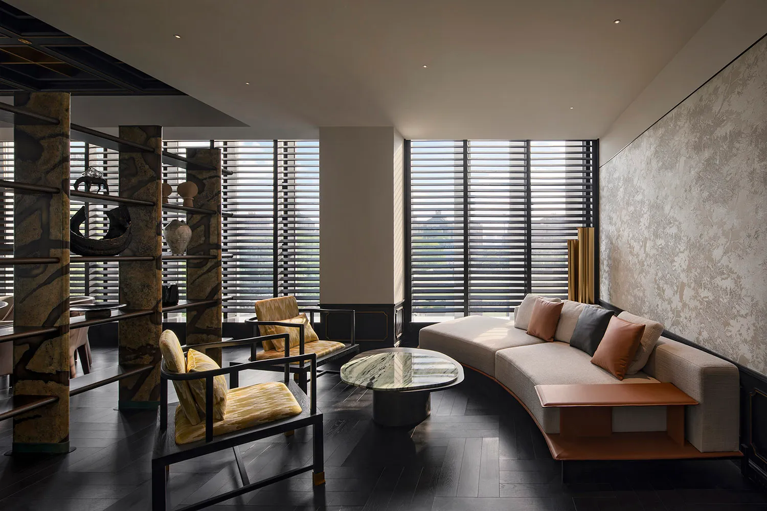 Modern living room with a curved sofa, armchairs, and a coffee table in a neutral-toned material setting.