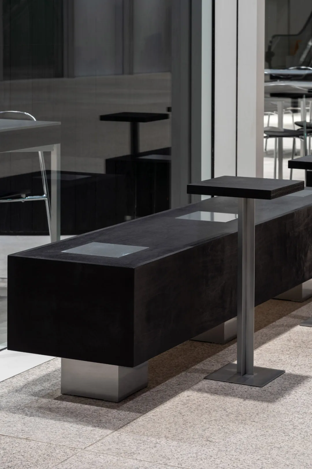 A modern public space furniture setup featuring concrete and metal elements.