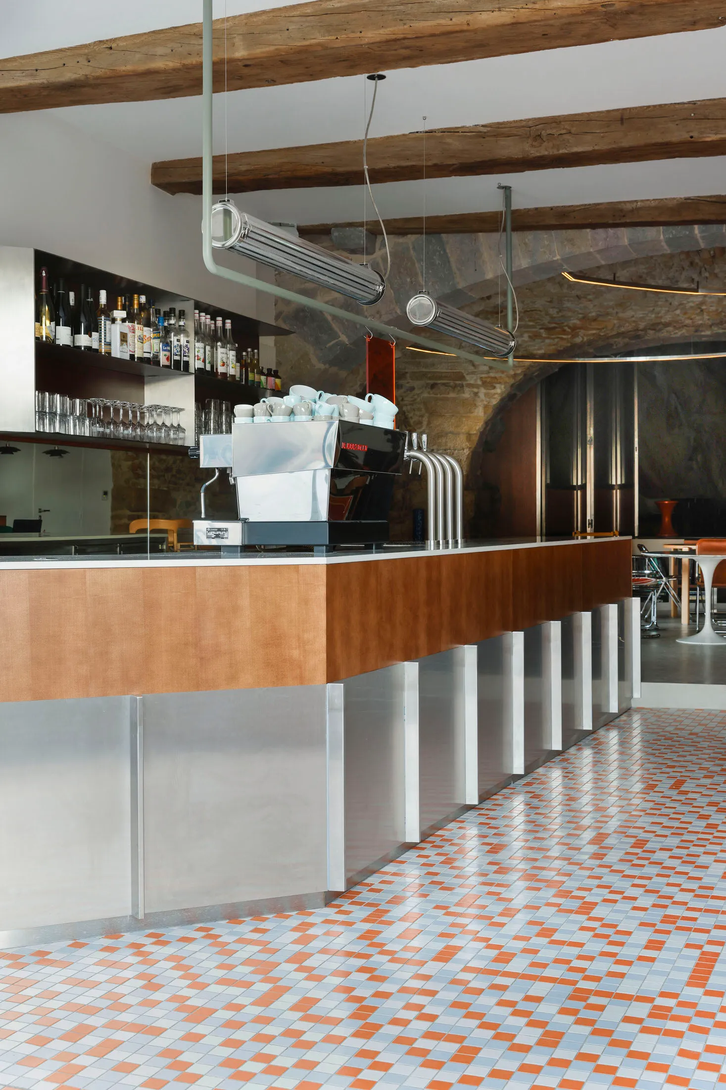 Industrial design cafe bar with metal counter, wooden seating, and stone walls.