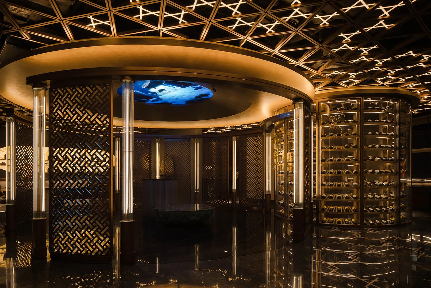A wine bar featuring a circular metal mesh structure with illuminated shelves and a central island with a blue light feature.