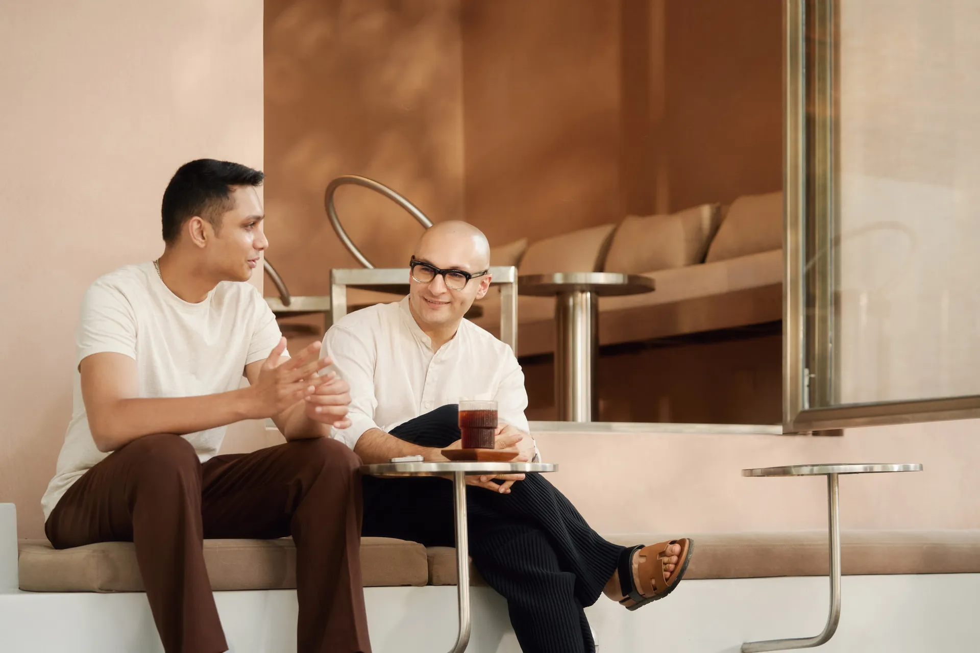 Two people sitting in a minimalist-designed coffee shop, engaged in a conversation.