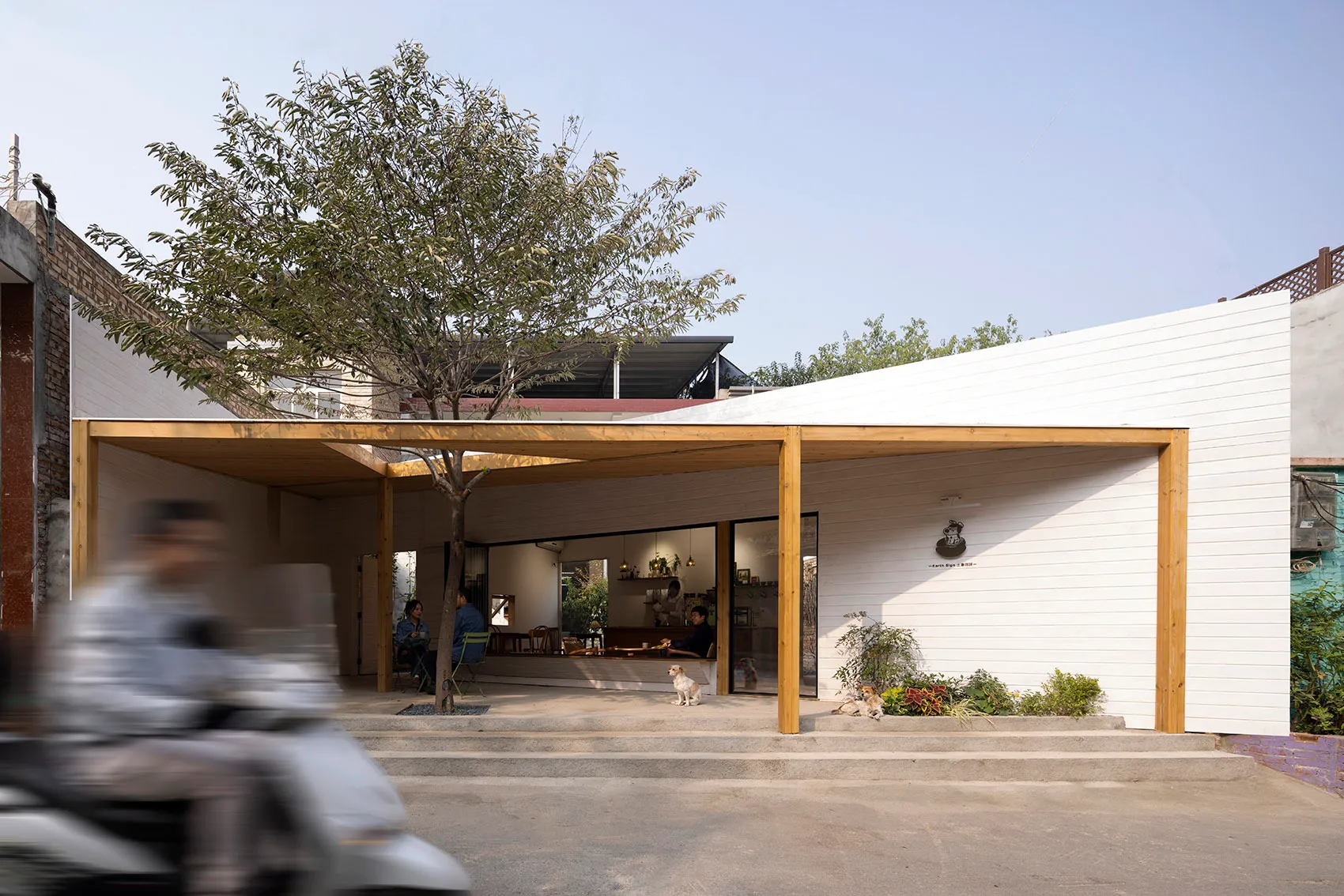 A minimalist restaurant exterior with white paneled walls and a wooden canopy.