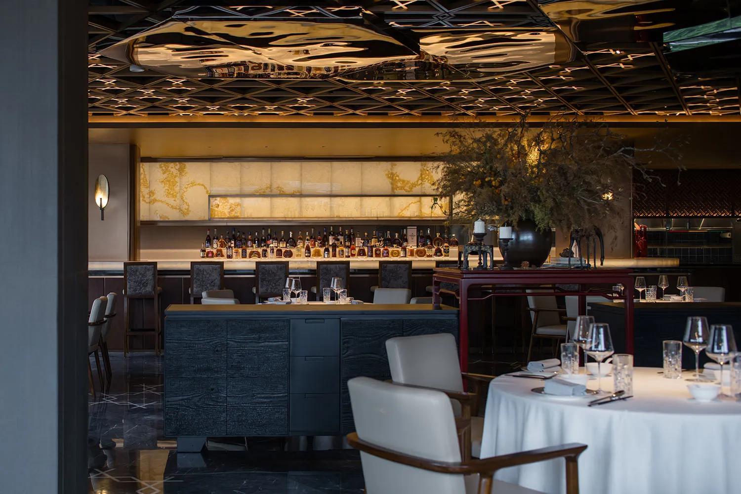 A modern restaurant bar with dark wood and stone finishes, featuring a luxurious interior design.