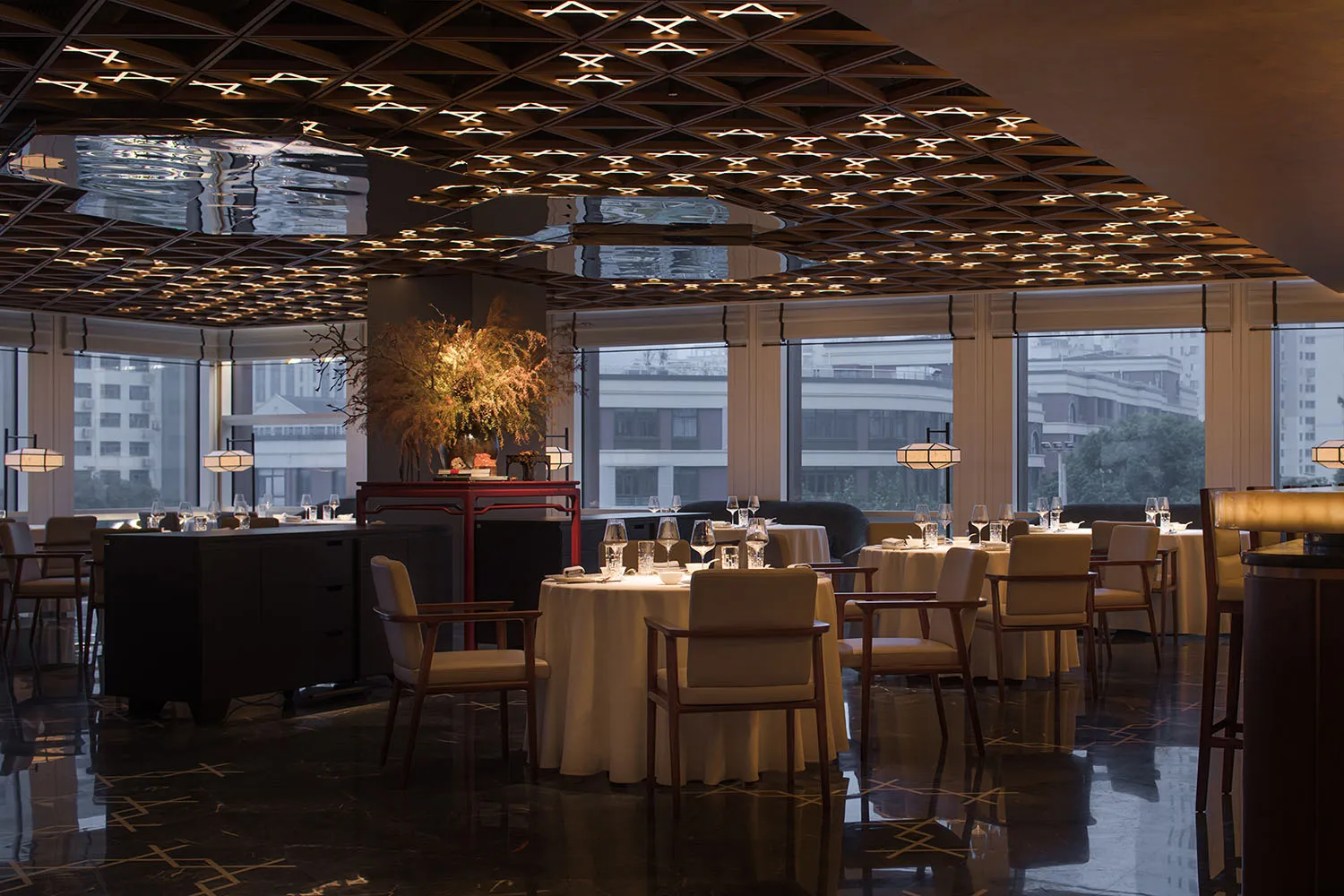 Modern restaurant interior with metal ceiling and round tables.