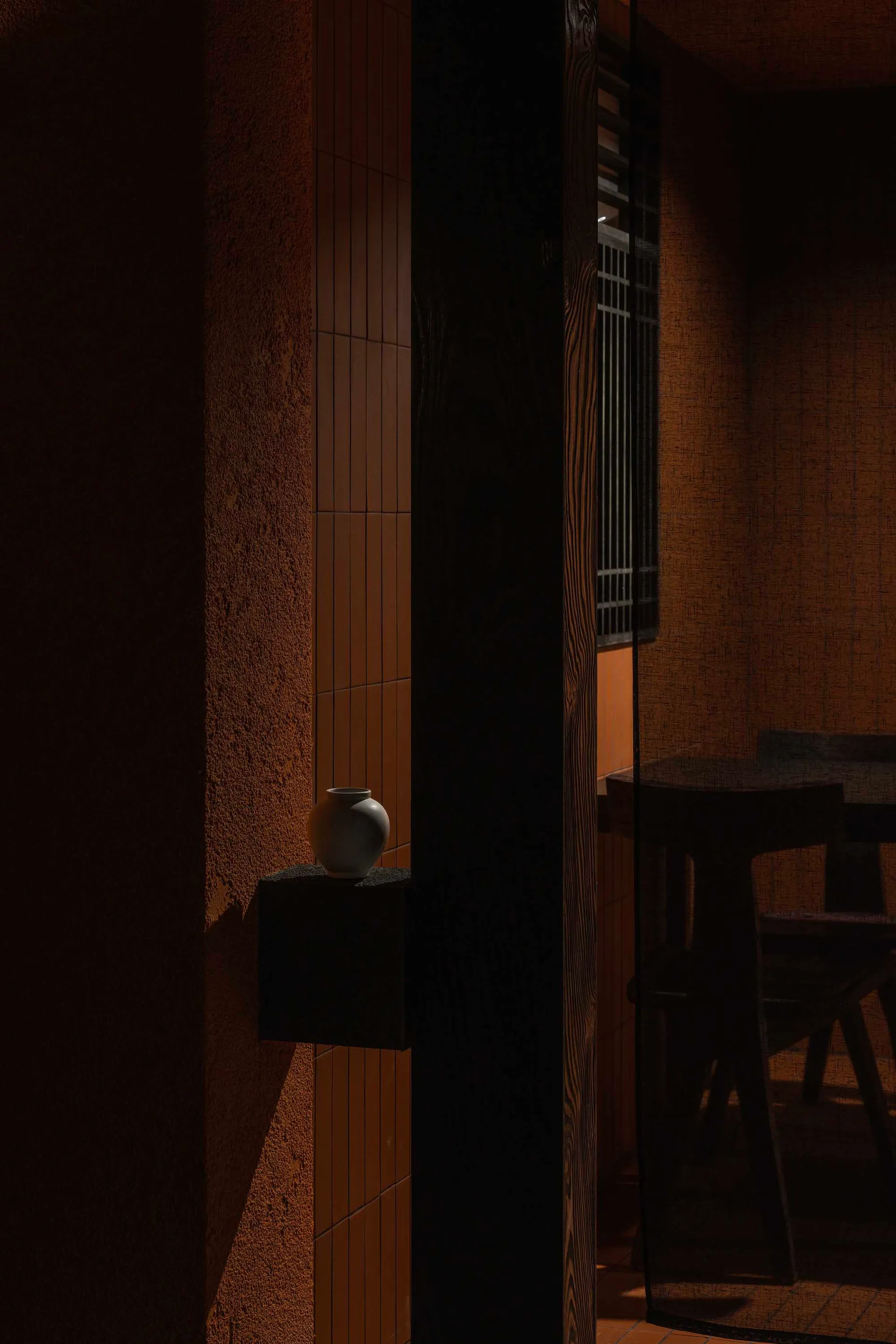 A dark interior setting featuring a ceramic vase on a shelf.